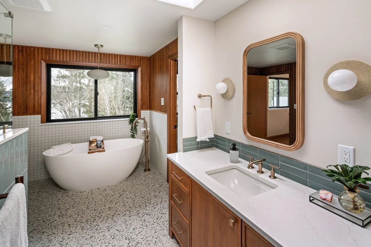 Mid-century modern bathroom remodel in Sammamish WA by a design-build contractor featuring a custom vanity, quartz countertop, green tile backsplash, and wood framed mirror
