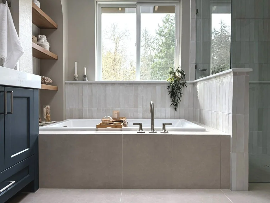 Soaking tub under large window with custom tile surround and built-in shelving in a Sammamish bathroom remodel