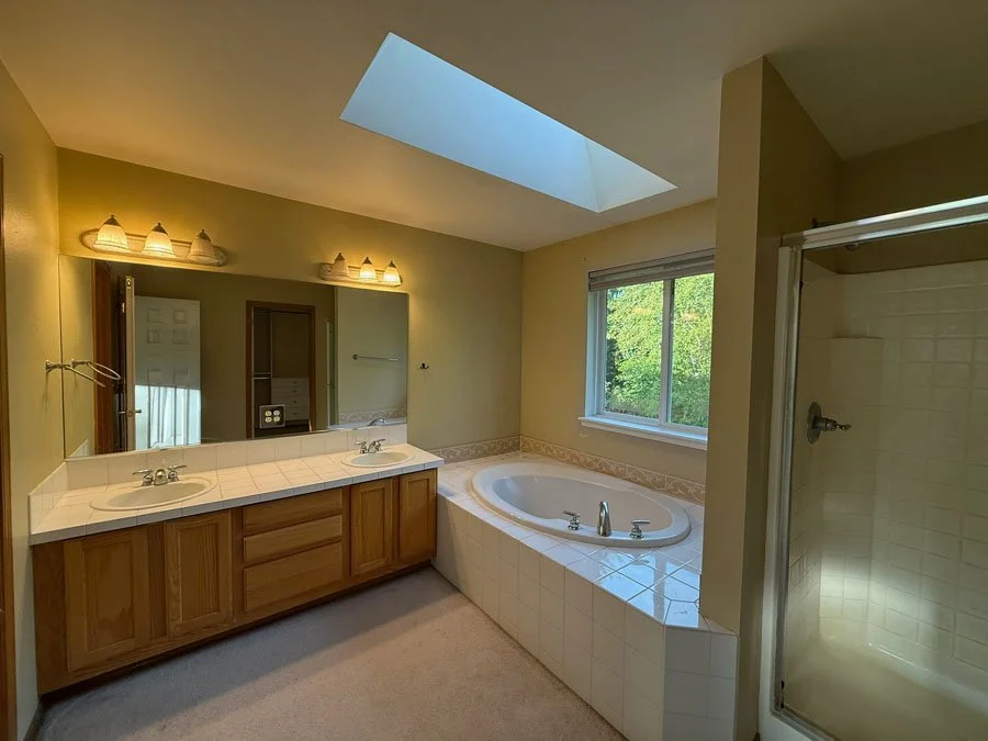 Before bathroom remodel in Sammamish WA with outdated vanity, drop-in tub, skylight, and enclosed shower
