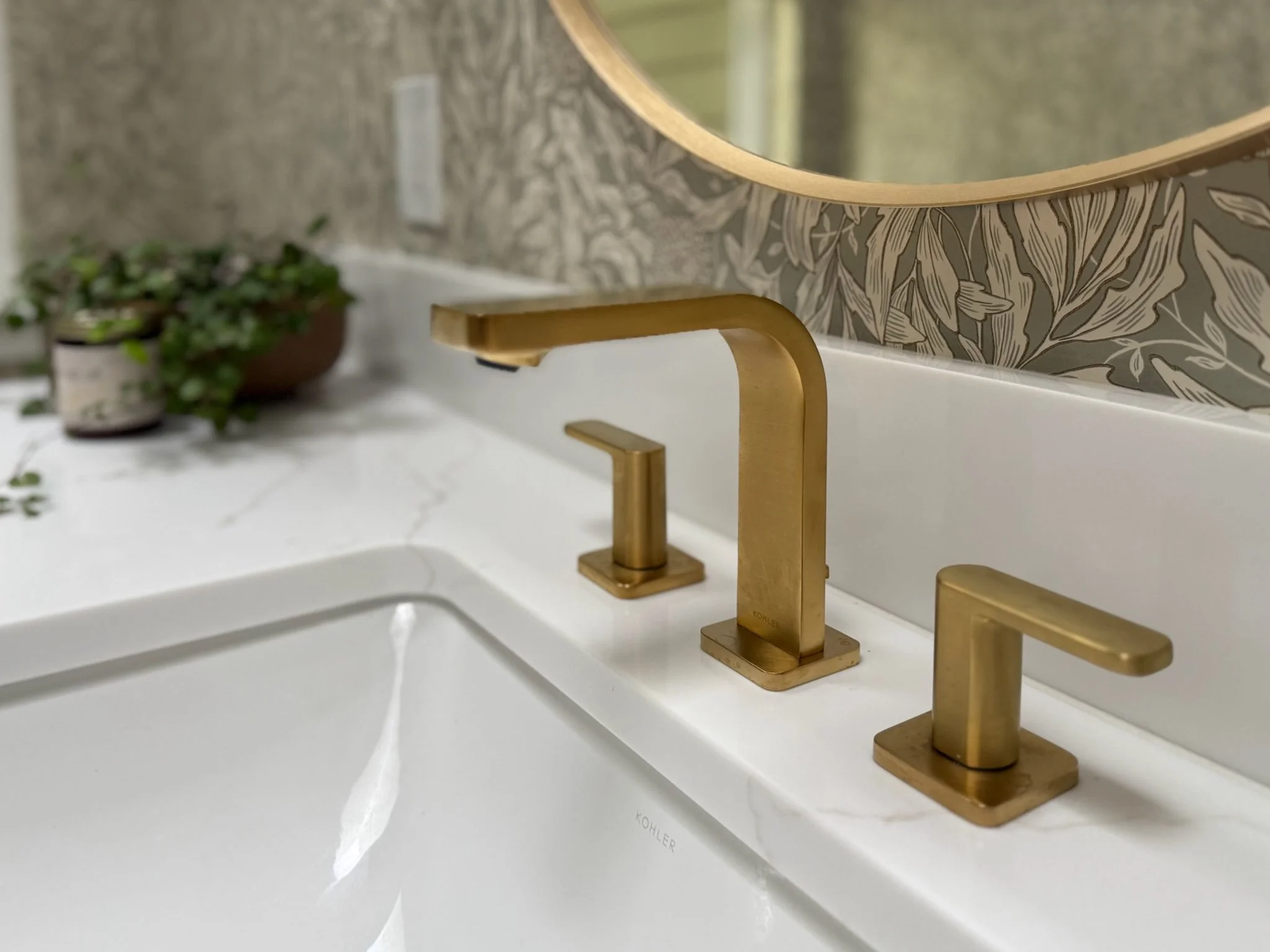 Close-up of the sink and brushed brass faucet in a Gig Harbor powder room remodel, designed and built by a remodeling contractor with coordinated countertop and tile finishes.