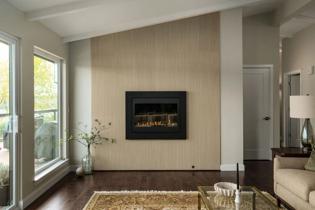 Living room fireplace feature wall in a Gig Harbor home remodel, redesigned by a remodeling contractor with vertical paneling and a modern black fireplace insert.
