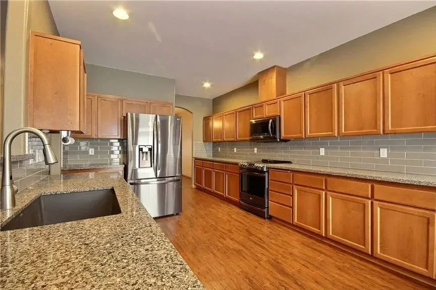 Before image of a kitchen in Lake Tapps, WA, featuring wood cabinets, granite countertops, stainless steel appliances, and a neutral backsplash prior to remodel.