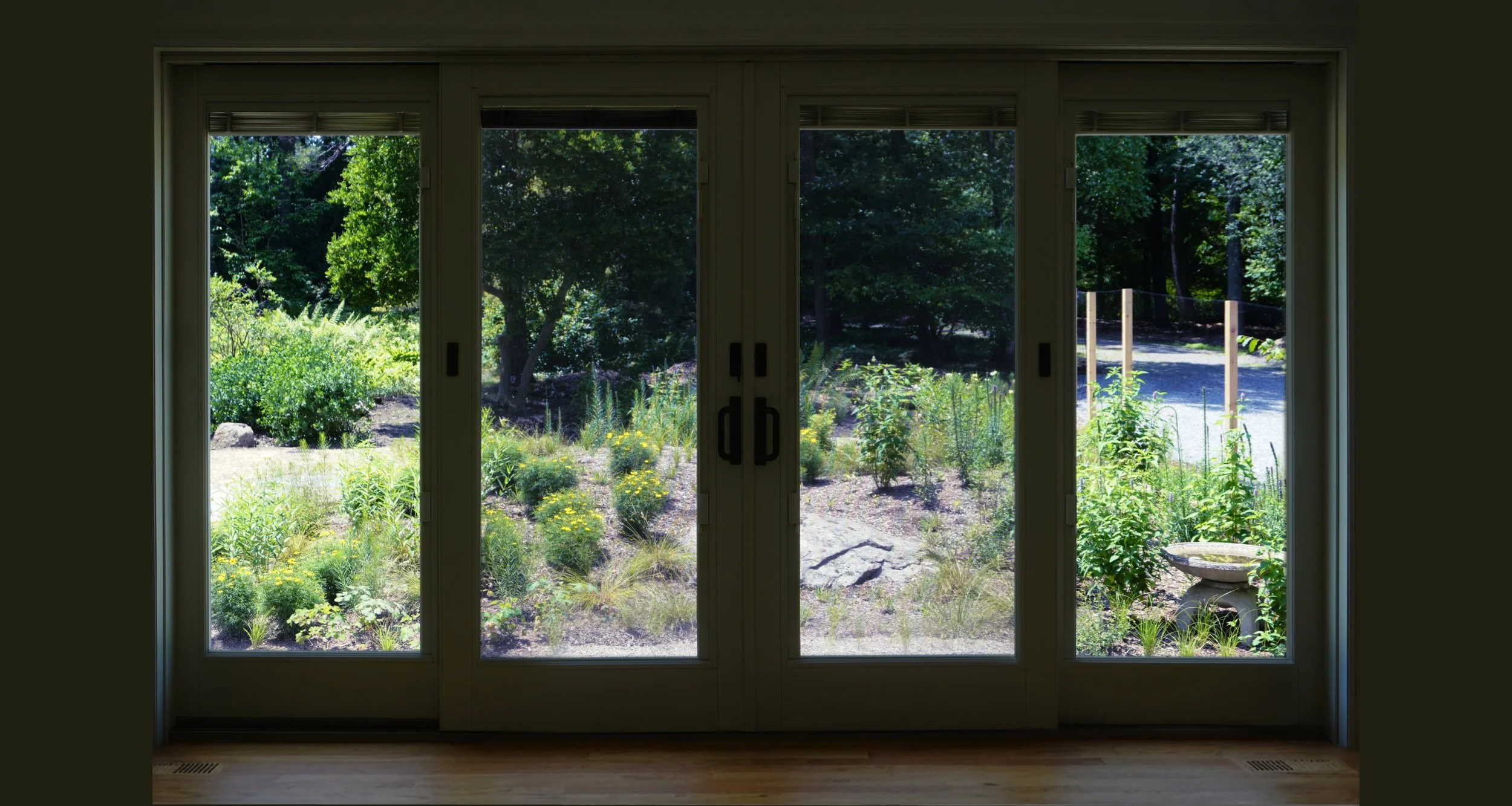 Native knoll looking out of a living room at perennials and local stone