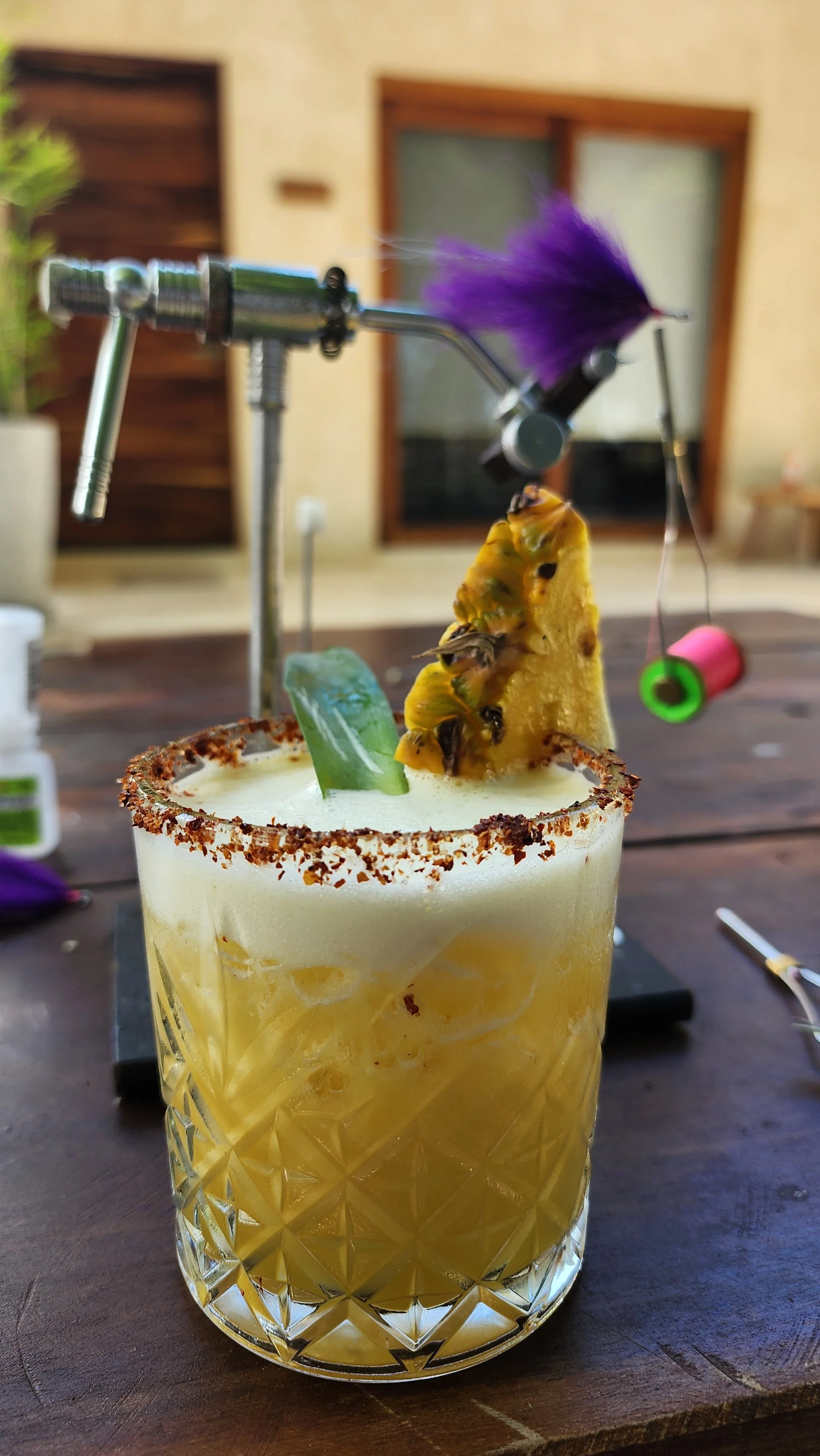 cocktail sits on table in front of fly tying gear at Xcalak Paradise Lodge 
