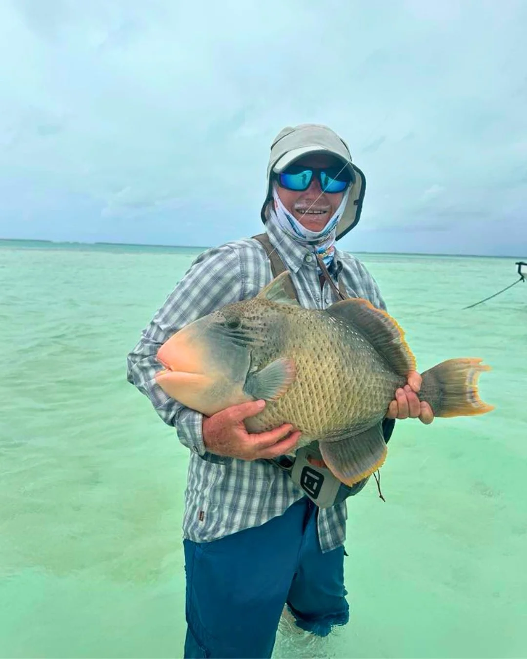 Angler and Guide hold a Giant Trevally on the bow of a boat in Christmas Island