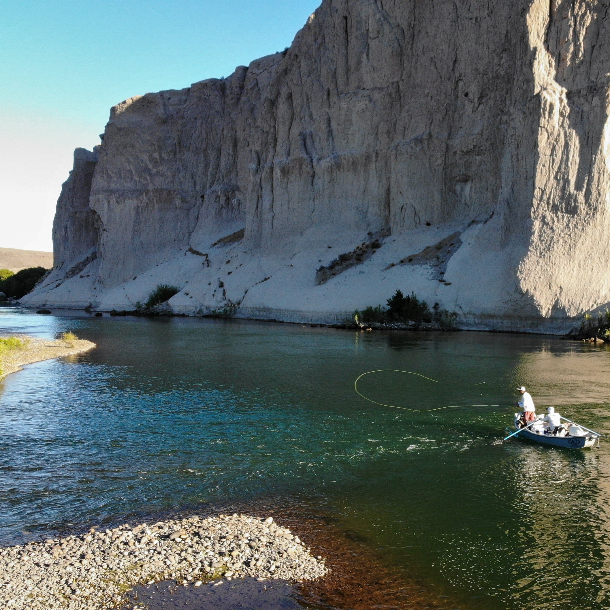 anger casts from drift boat in Northern Patagonia as guide rests the oars