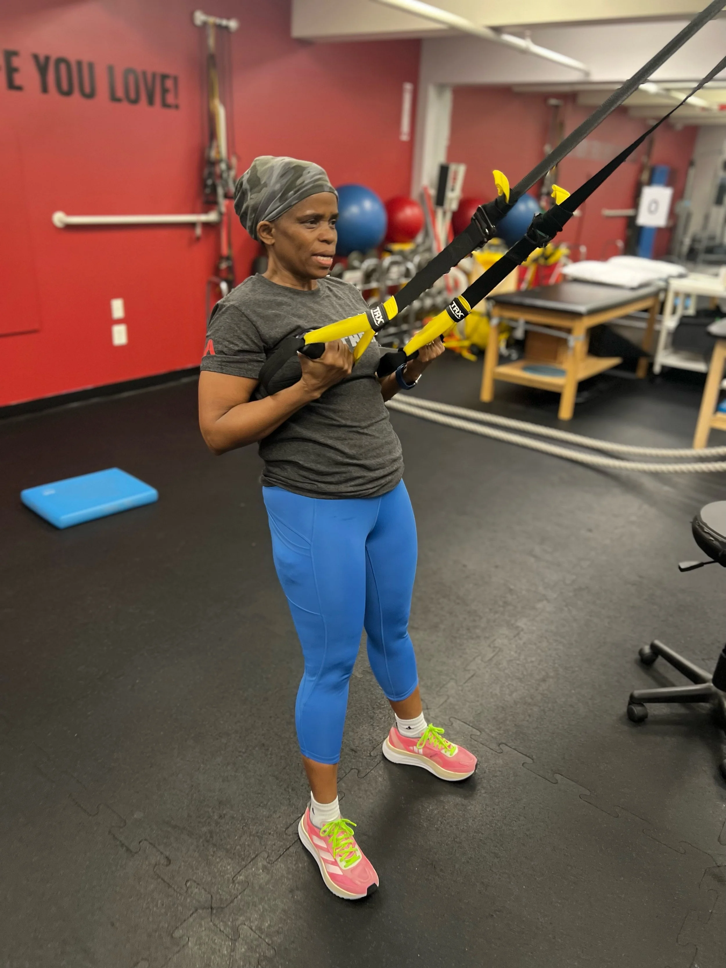 Person exercising with TRX suspension straps in a gym.