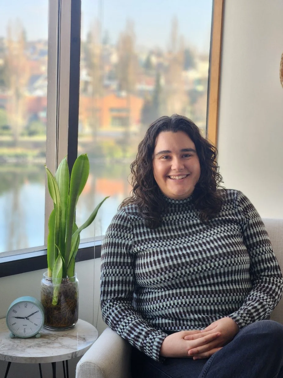 A Seattle therapist who specializes in ADHD and religious trauma sits in her Queen Anne office, with a plant next to her and the Fremont Canal visible outside the window.