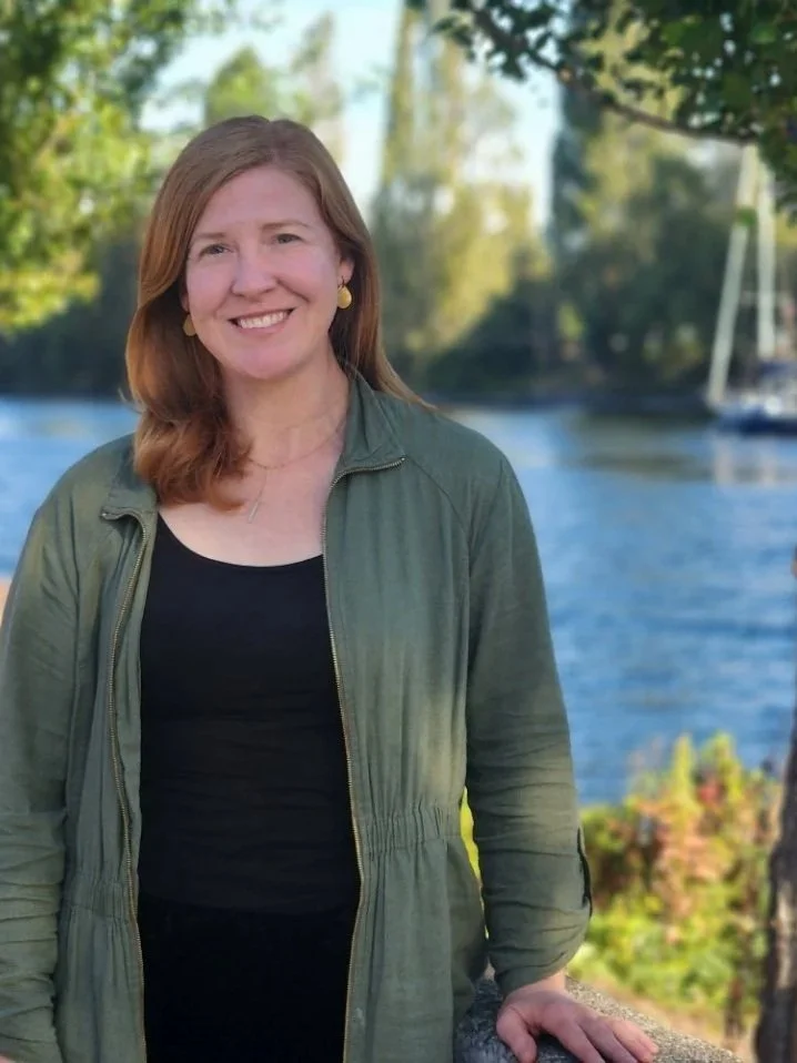 Kate, a Riverbank Therapy counselor, smiling warmly outdoors along Seattle's Lake Washington waterfront