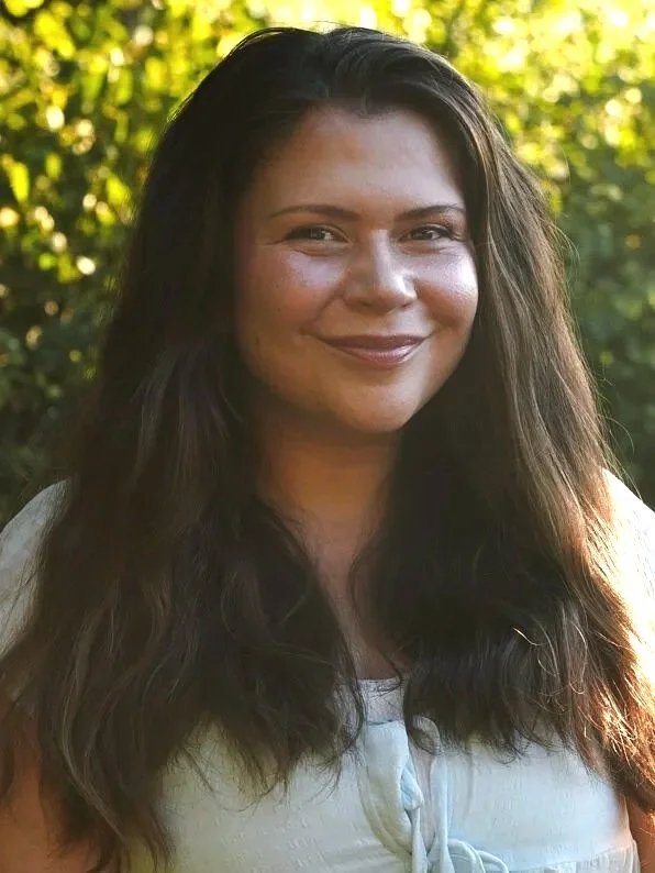 Seattle grad student low cost therapist stands outside in Fremont near some green trees.