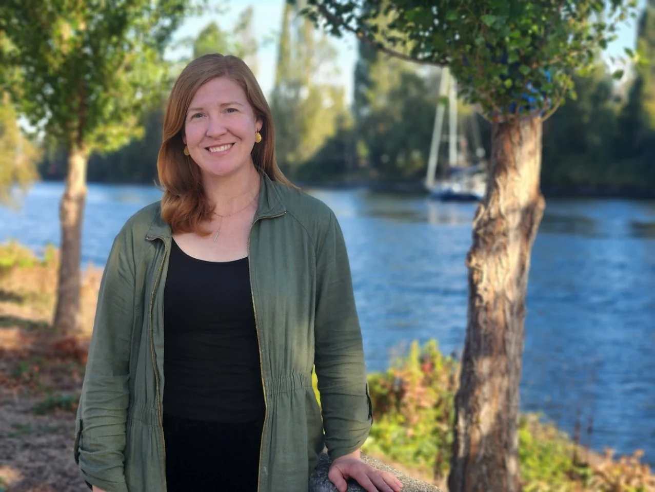 Kate, a therapist in seattle who specializes in grief and loss, couples therapy, and family therapy, stands outside by the canal in queen anne.