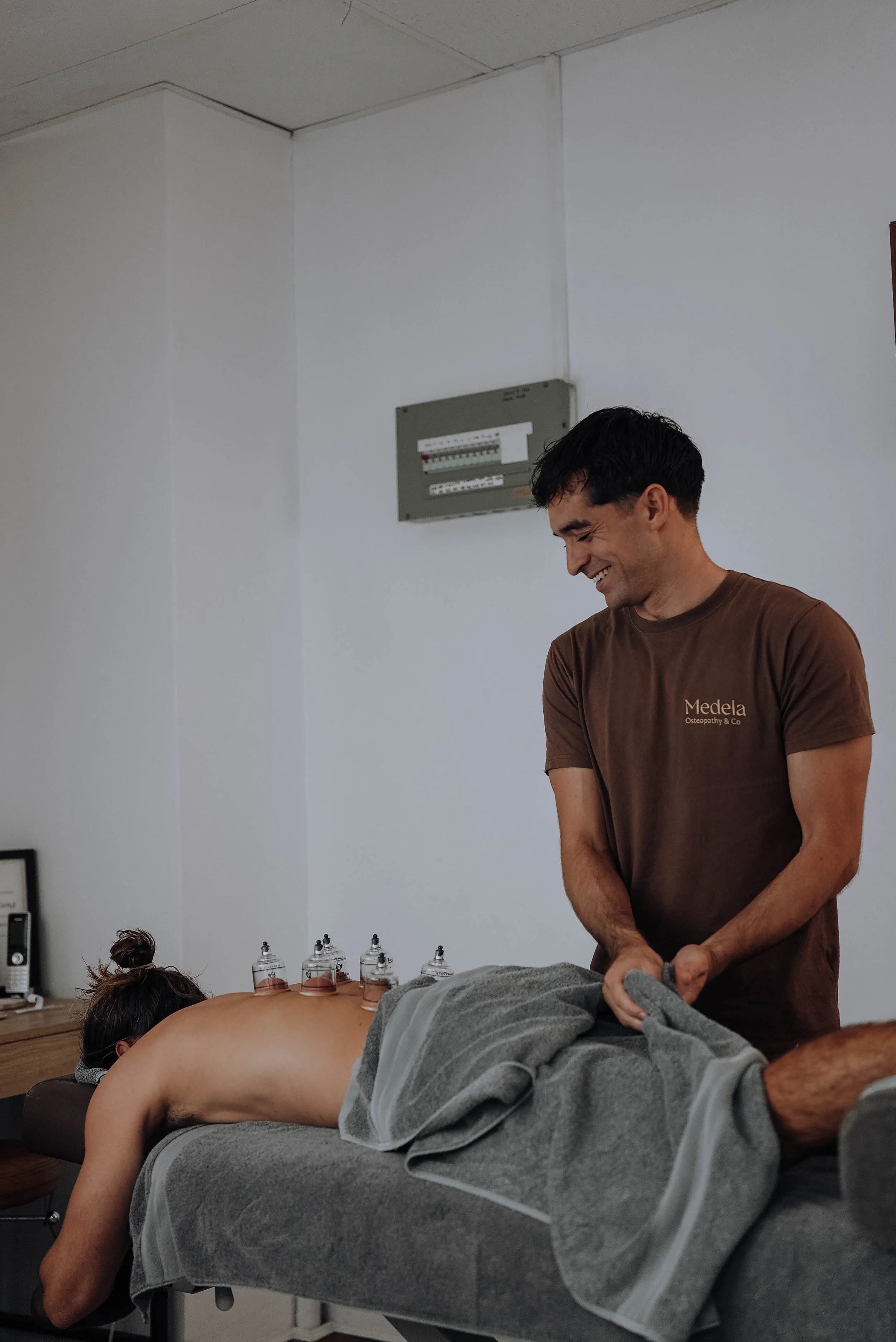 Osteopath at Medela Osteopathy & Co treating a patient's back and upper body with cupping at the Tweed Heads clinic
