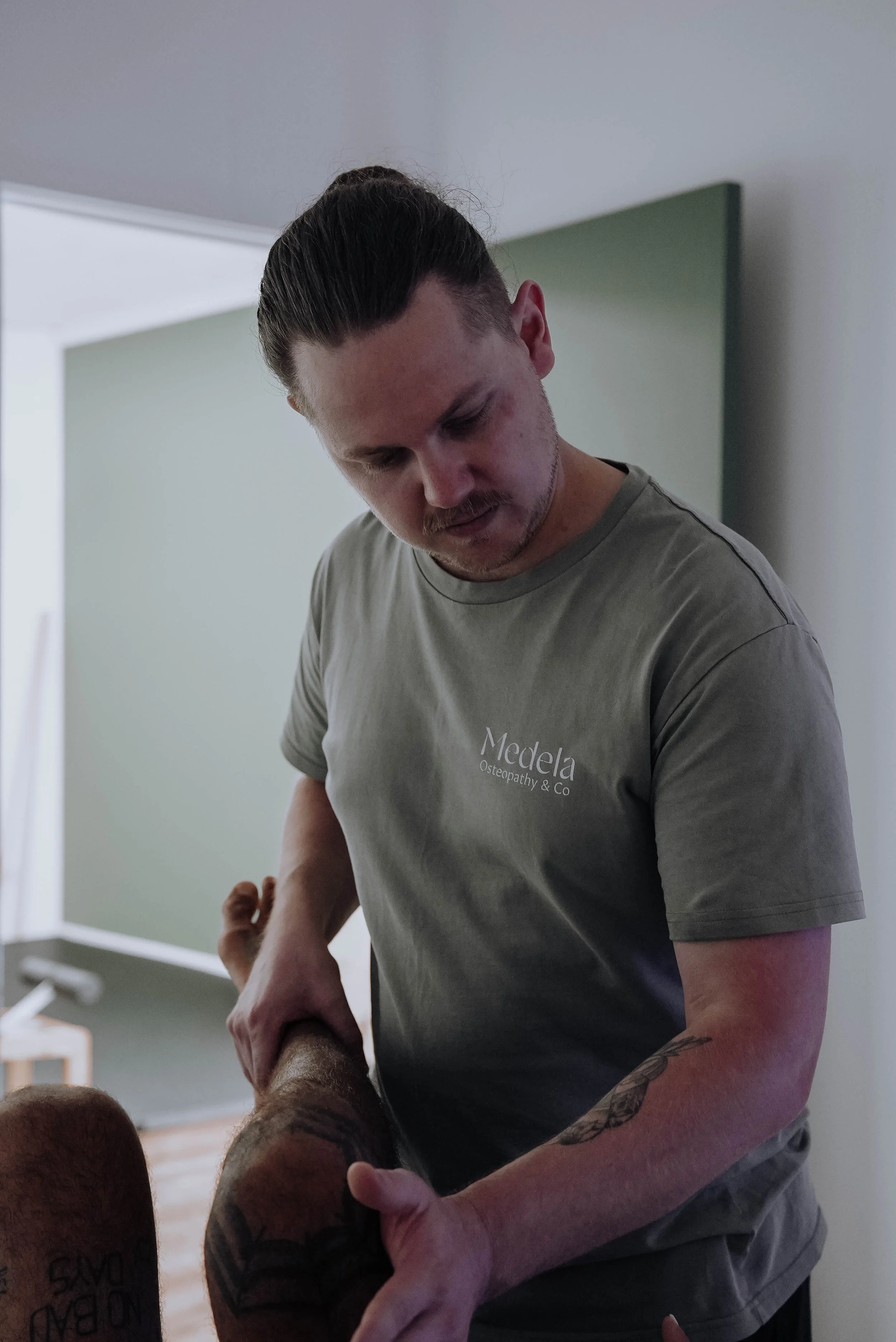 Remedial massage therapist Zach Brown treating a patient's leg at Medela Osteopathy & Co in Tweed Heads