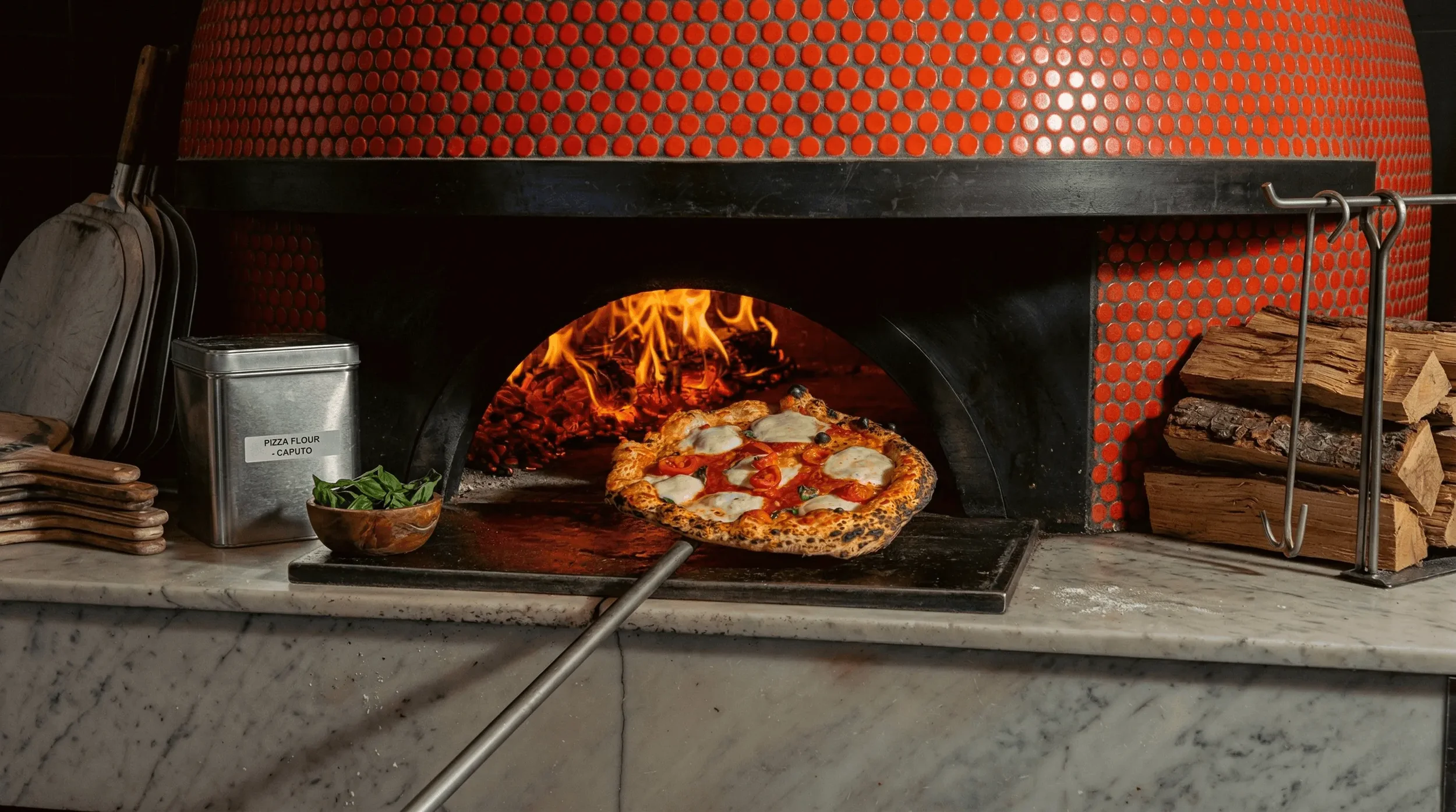 Close-up of a wood fired Margherita pizza with charred cornicione and bubbling mozzarella