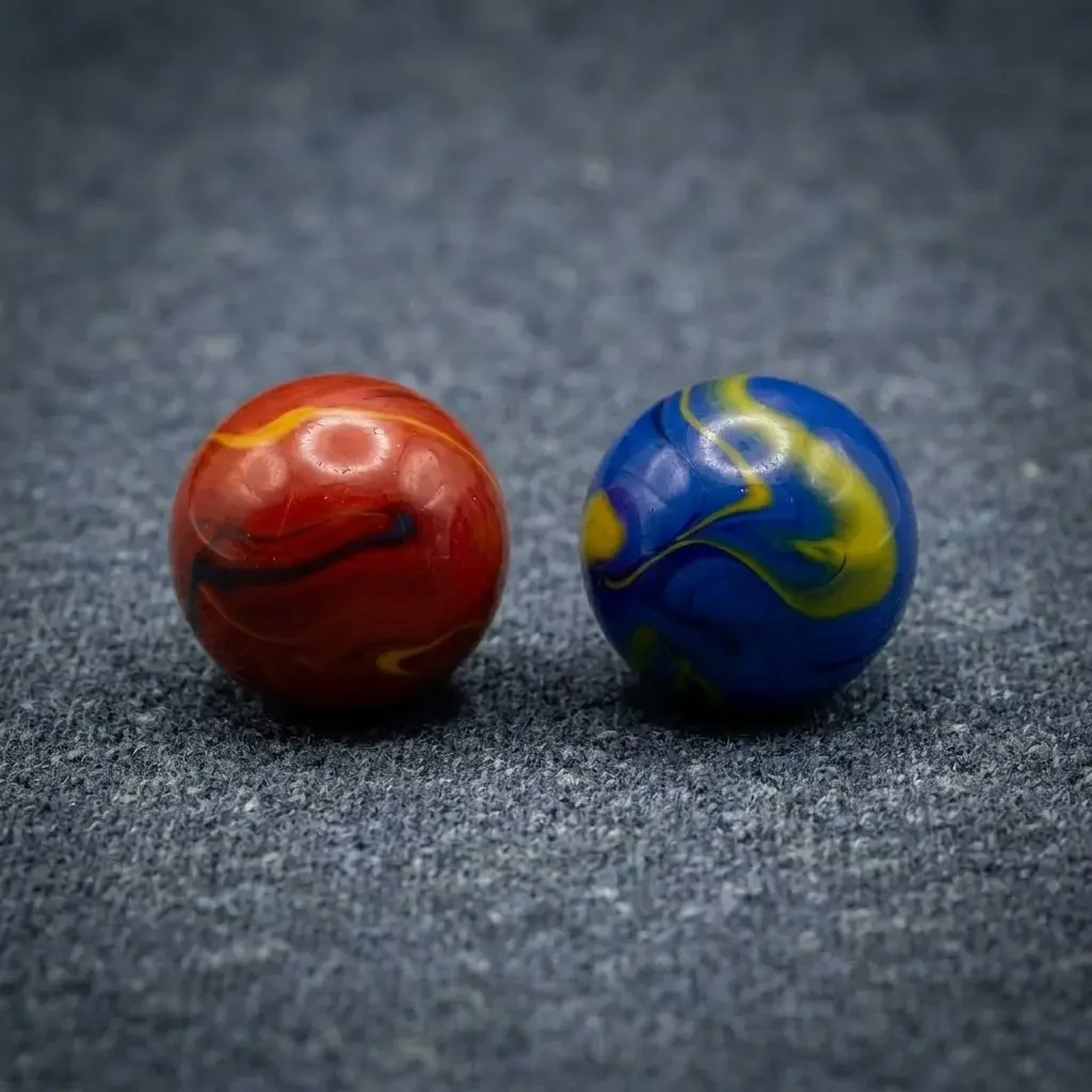 Focused, square cinematic shot of red and blue taw marbles placed on heather slate grey carpeted surface