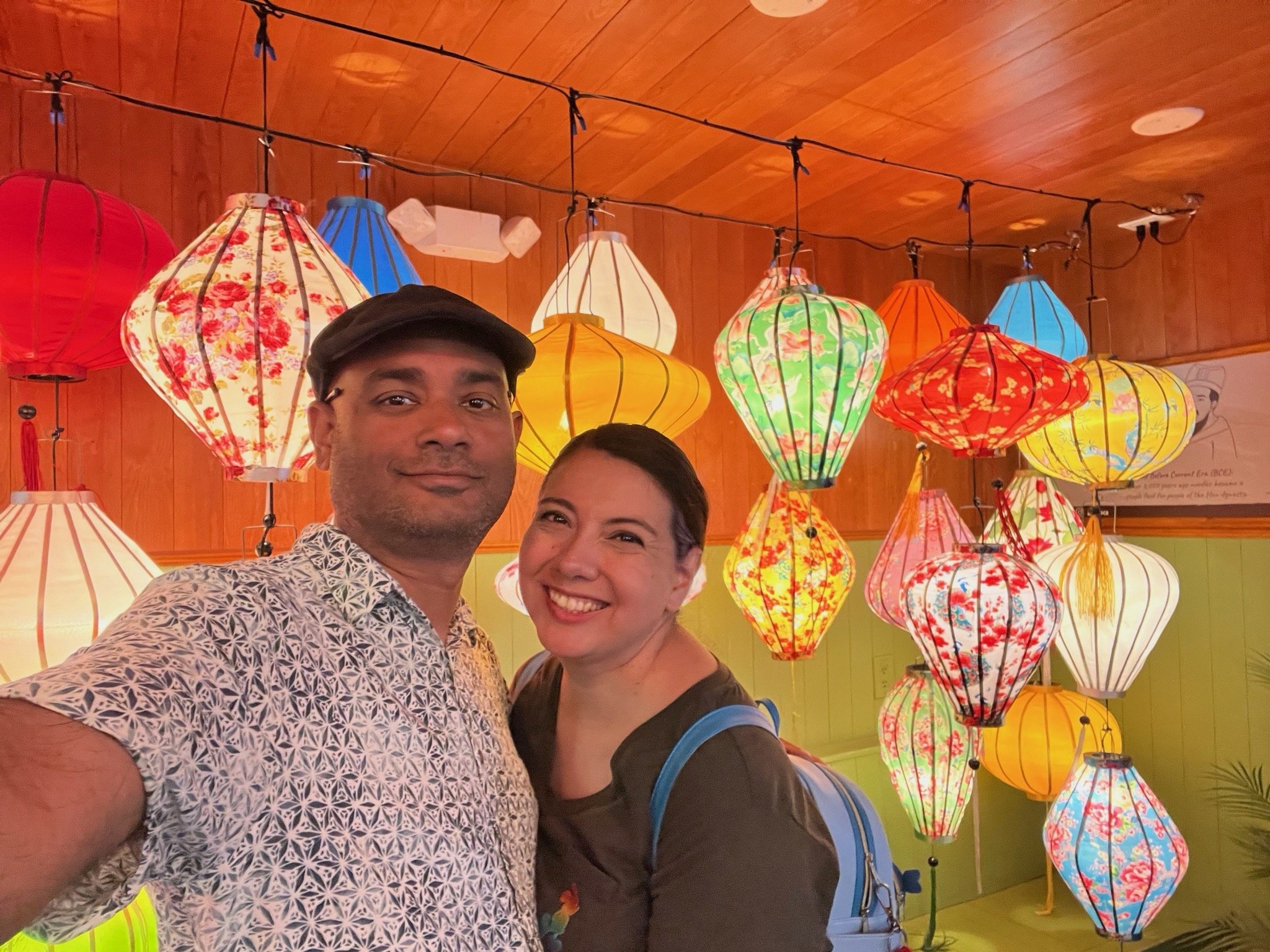 A smiling Ruwan and Diana taking a selfie in front of colorful hanging lanterns.