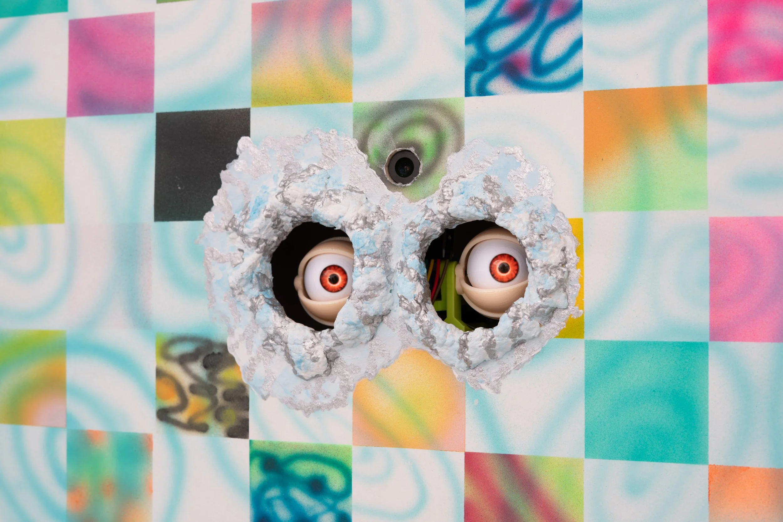 Simone Siegel,  ALTA CLOCKER  (detail), 2025. Acrylic on paper mounted on panel in upholstered textile frame, clay, plastic eyeballs, electronics, 57 x 47 x 5 1/2 in. Electronics consulting and fabrication by Lee Matos.