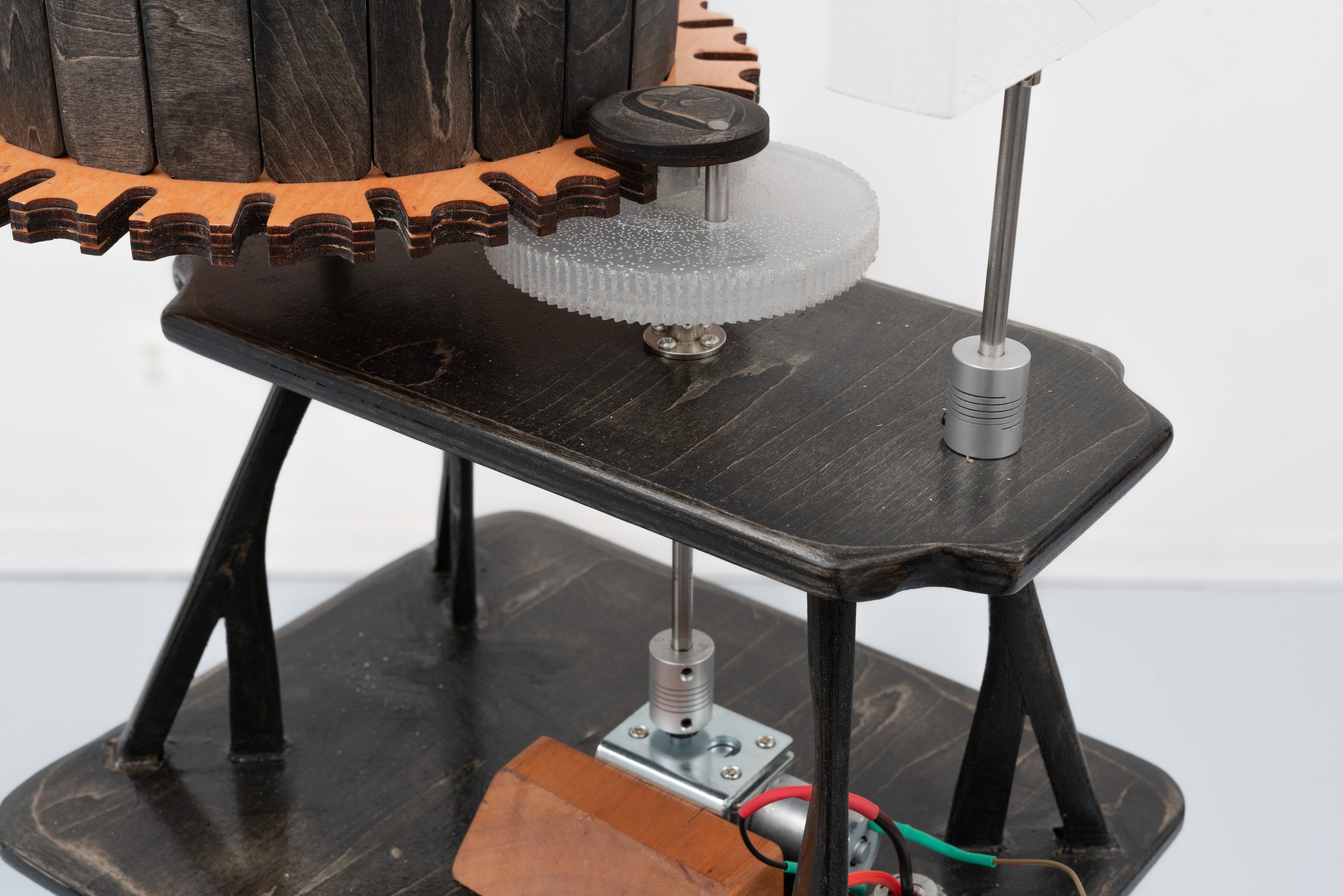 Pat Reynolds,  Slow Crawl , 2025–2026 (detail). Basswood, maple, steel, resin, cement, copper, inkjet prints, fresnel lens, DC motor, hardware, wires, material lift; 24 frames, approximately 24 seconds per full rotation; 64 x 64 x 58 in (height varia