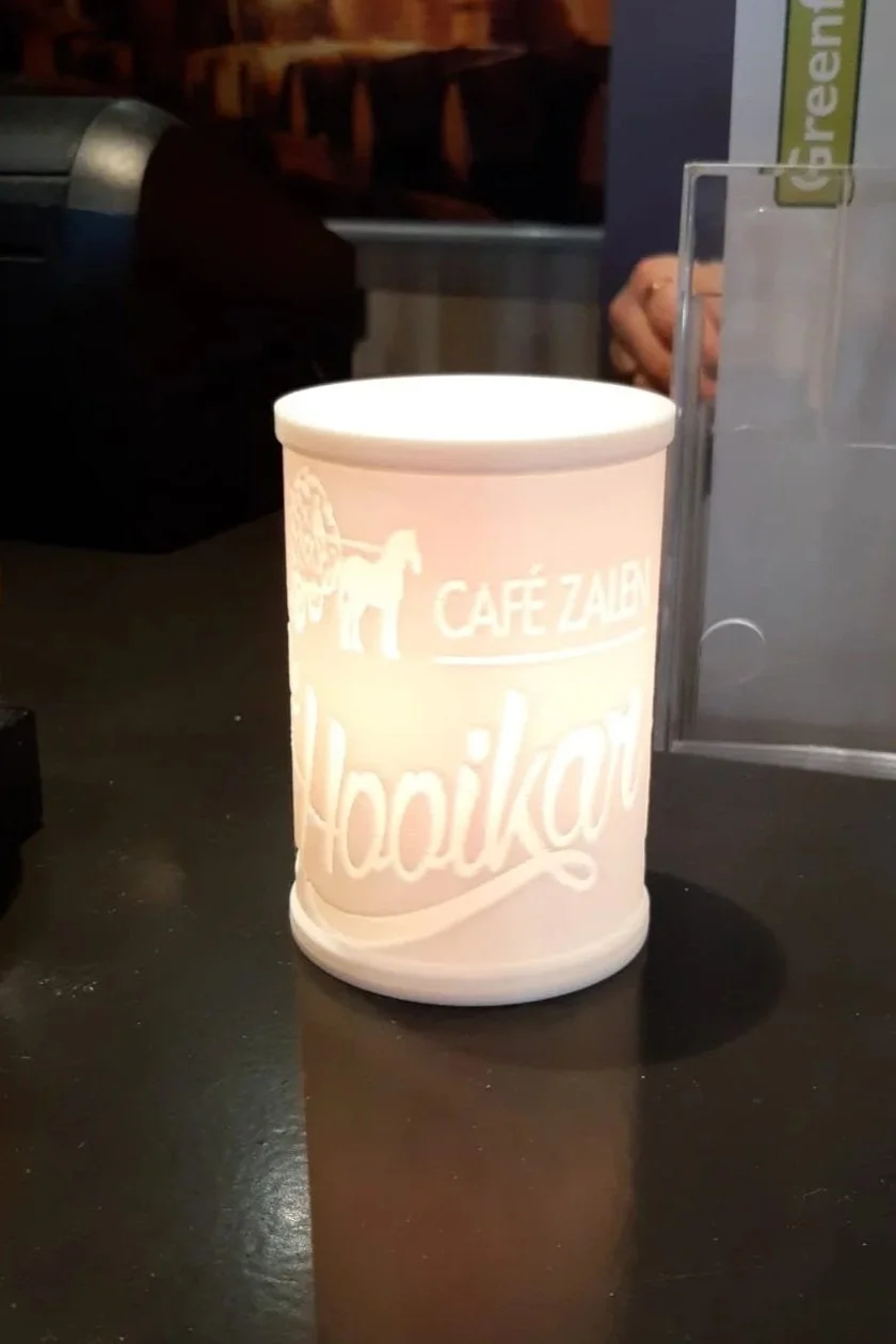 Verlichte kaarshouder met logo van restaurant "De hooikar".