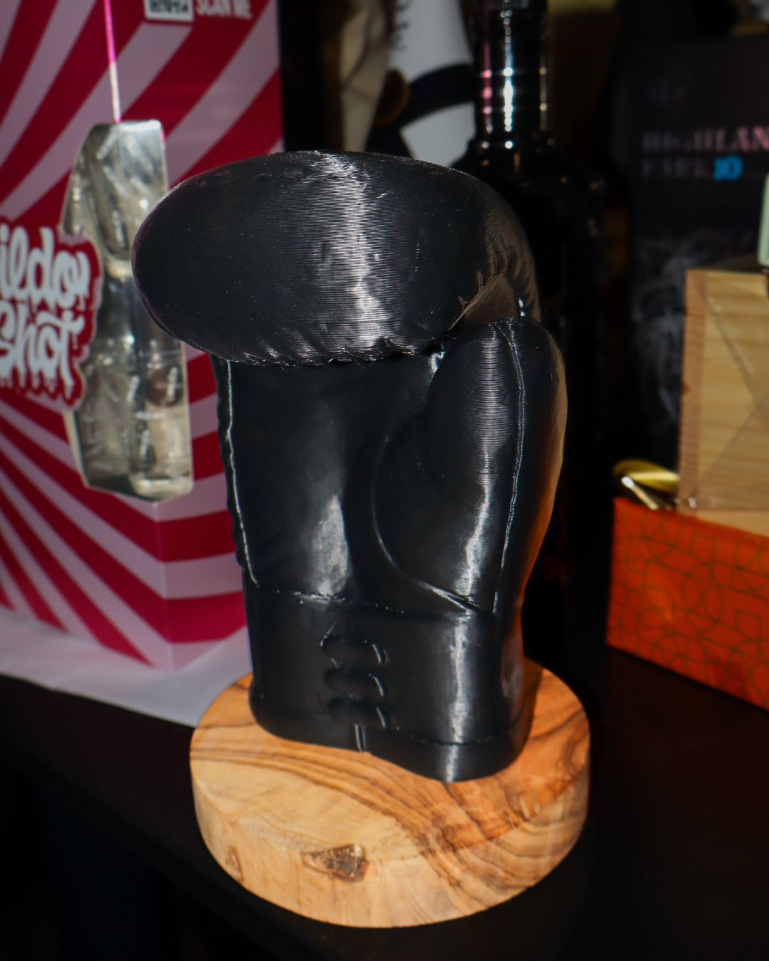 Een 3D geprinte zwarte bokshandschoen op een houten blad met het logo van private gym Paulo Boer