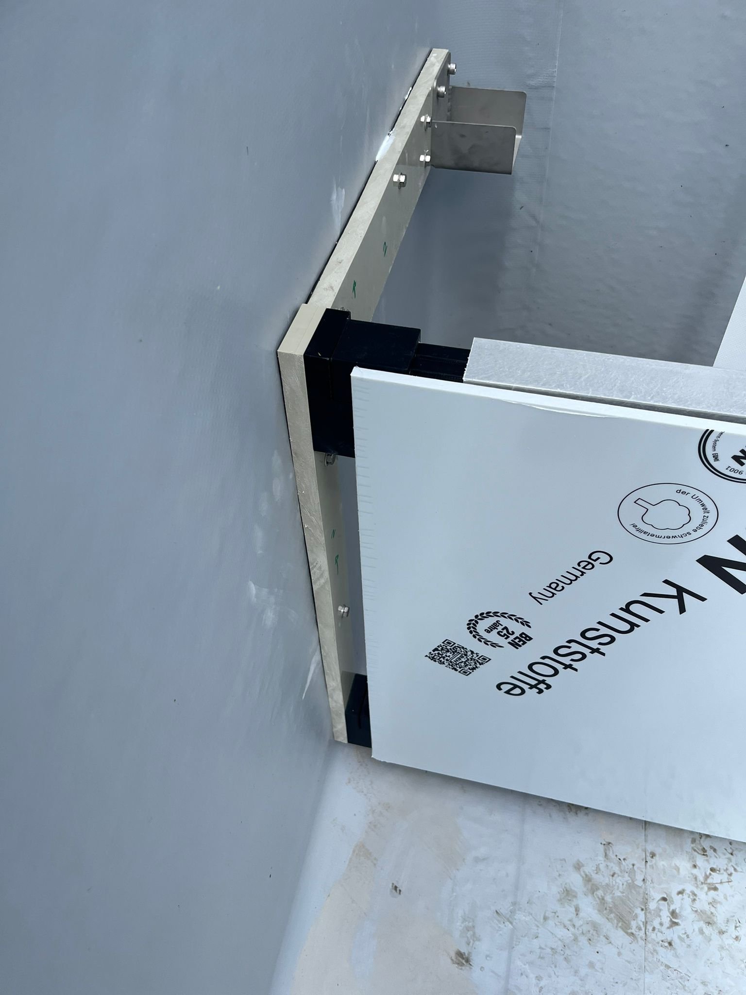 Close-up van een technische installatie met metalen en kunststof onderdelen en bevestigingsmiddelen, geïnstalleerd op een muur en vloer van een zwembad.