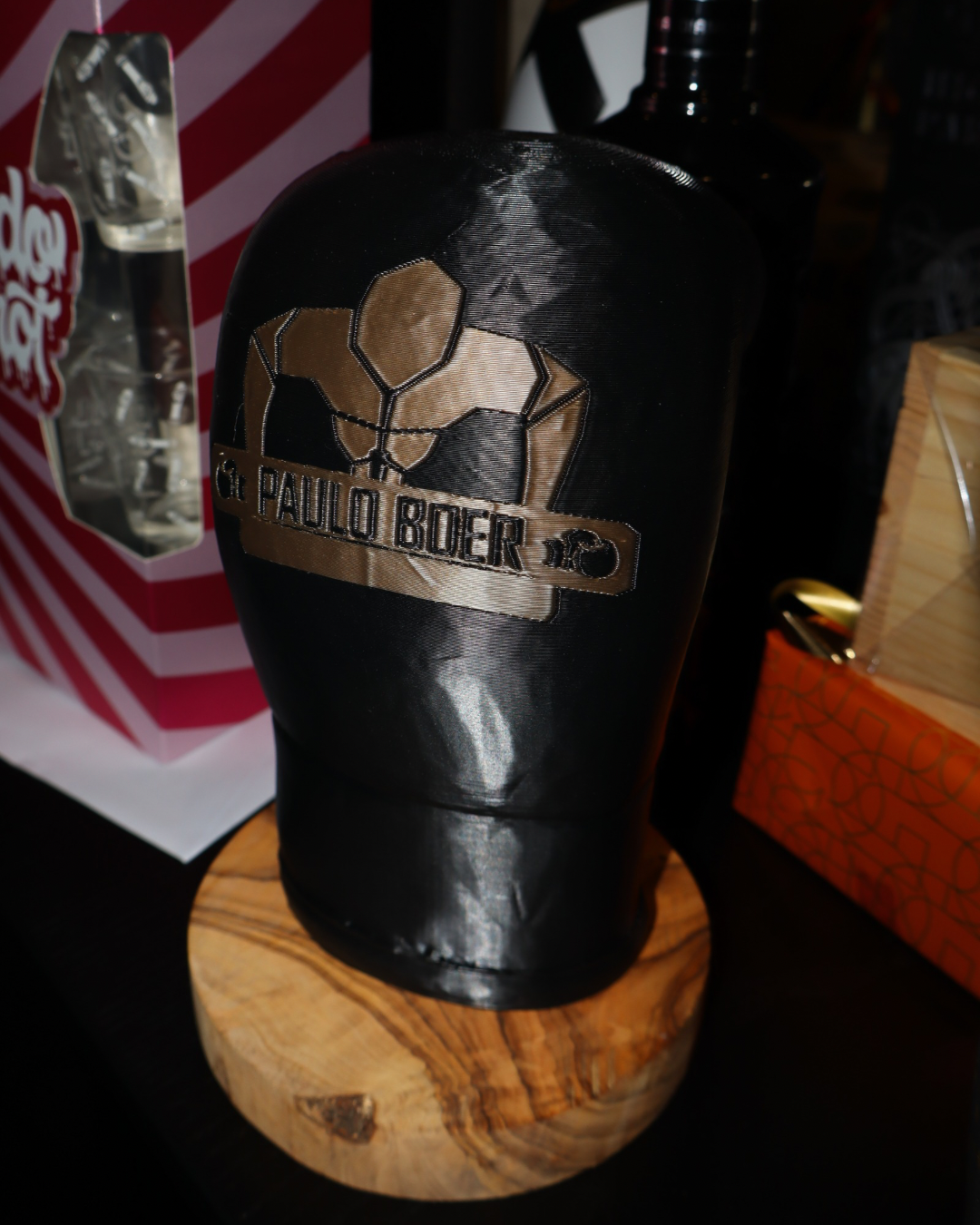 Een 3D geprinte zwarte bokshandschoen op een houten blad met het logo van private gym Paulo Boer