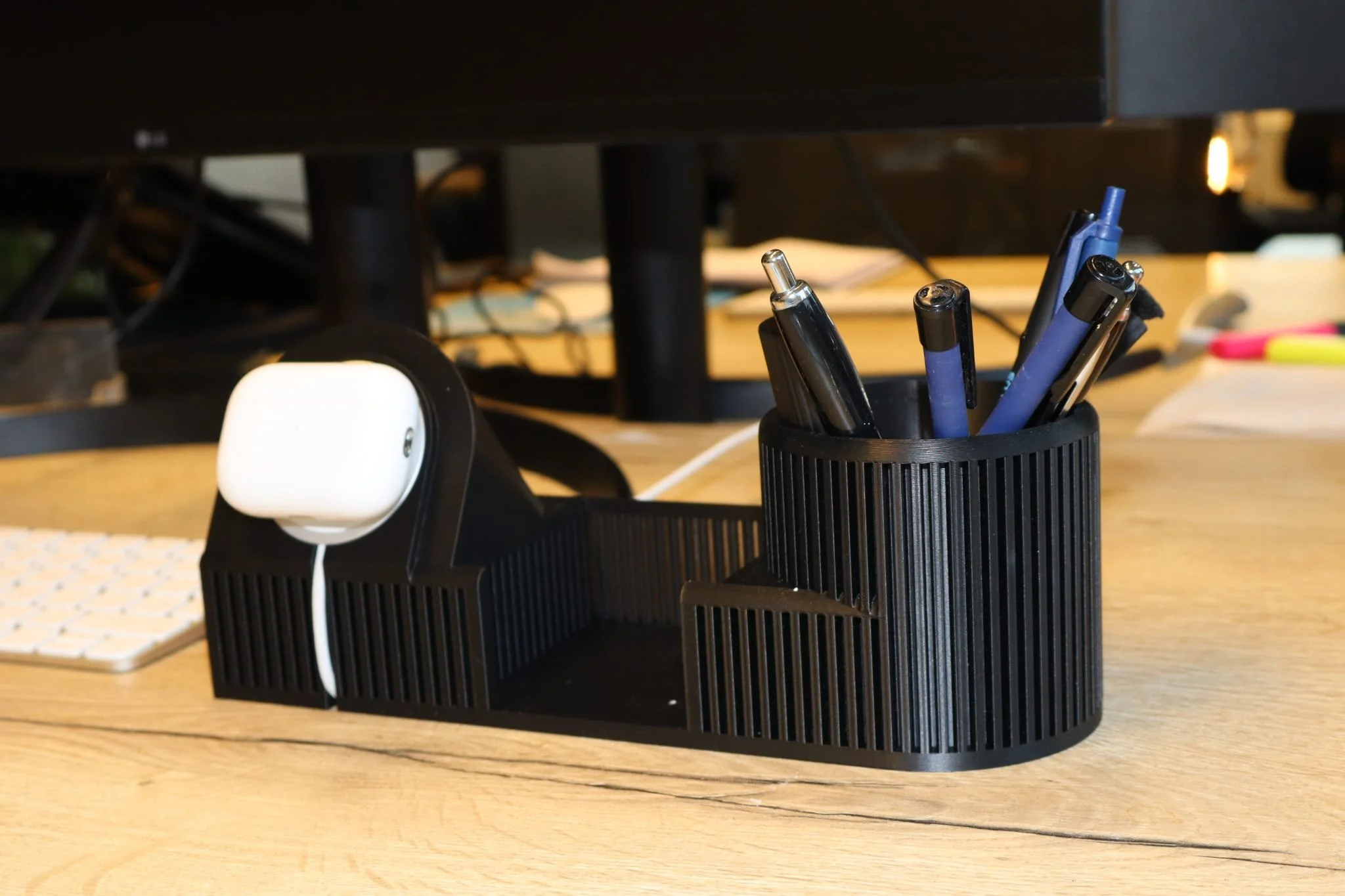 Een bureau- of tafelorganizer met pennen en een oplaadstation met Magsafe voor AirPods en Iphone opladen op een houten bureau.