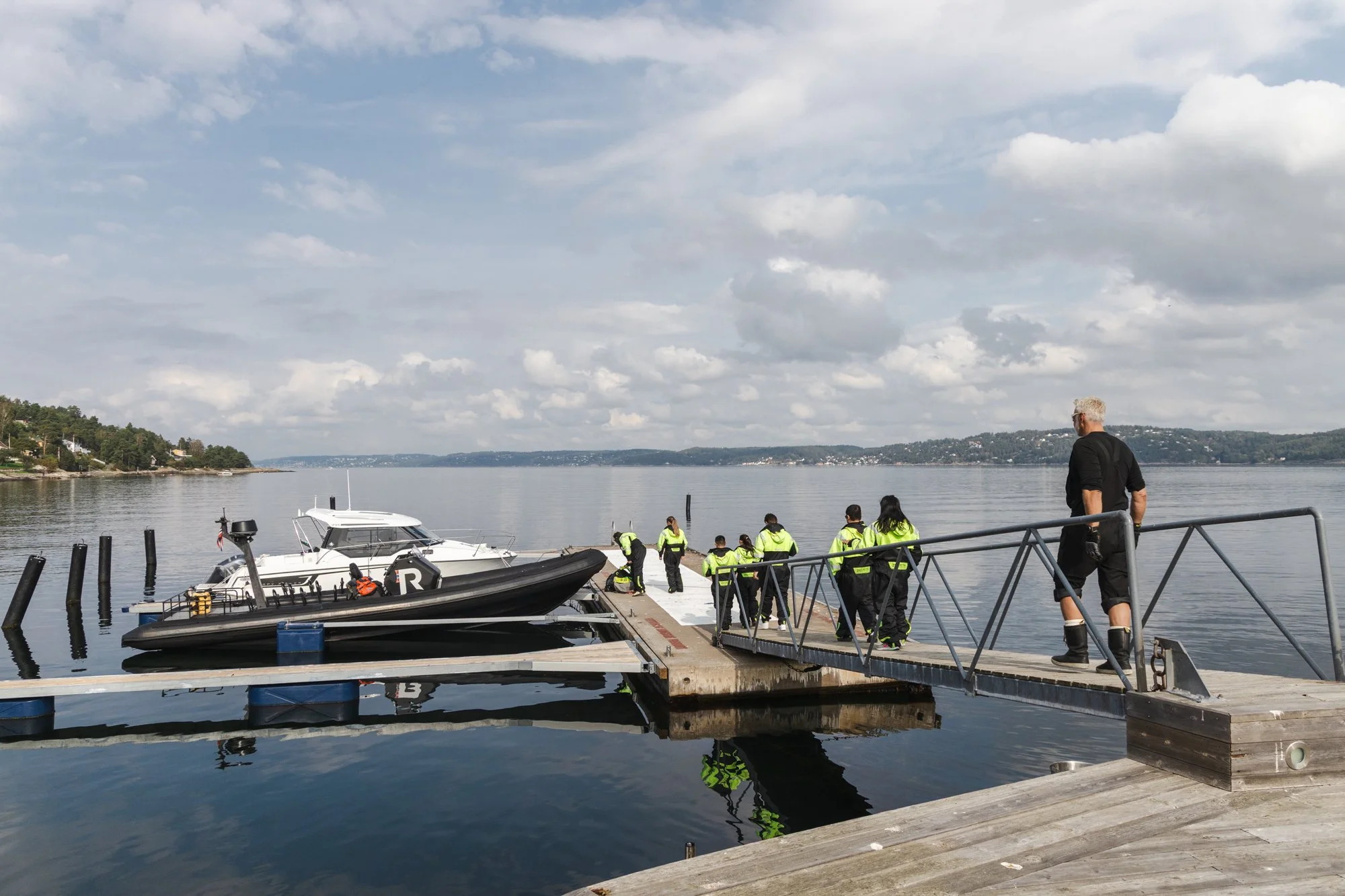 Mennesker som går nedover en brygge mot to båter.