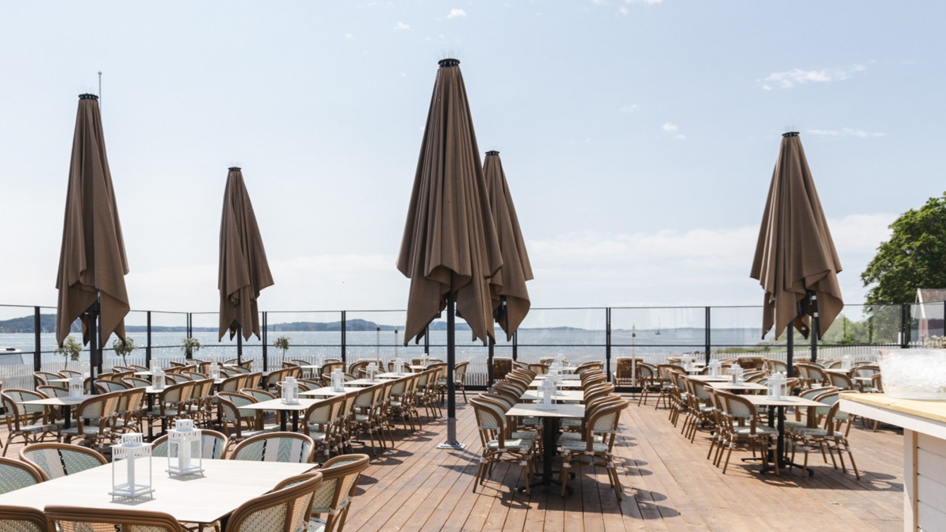 Uteserveringen på Vilma Sjøbad med bord og stoler langs fjorden.