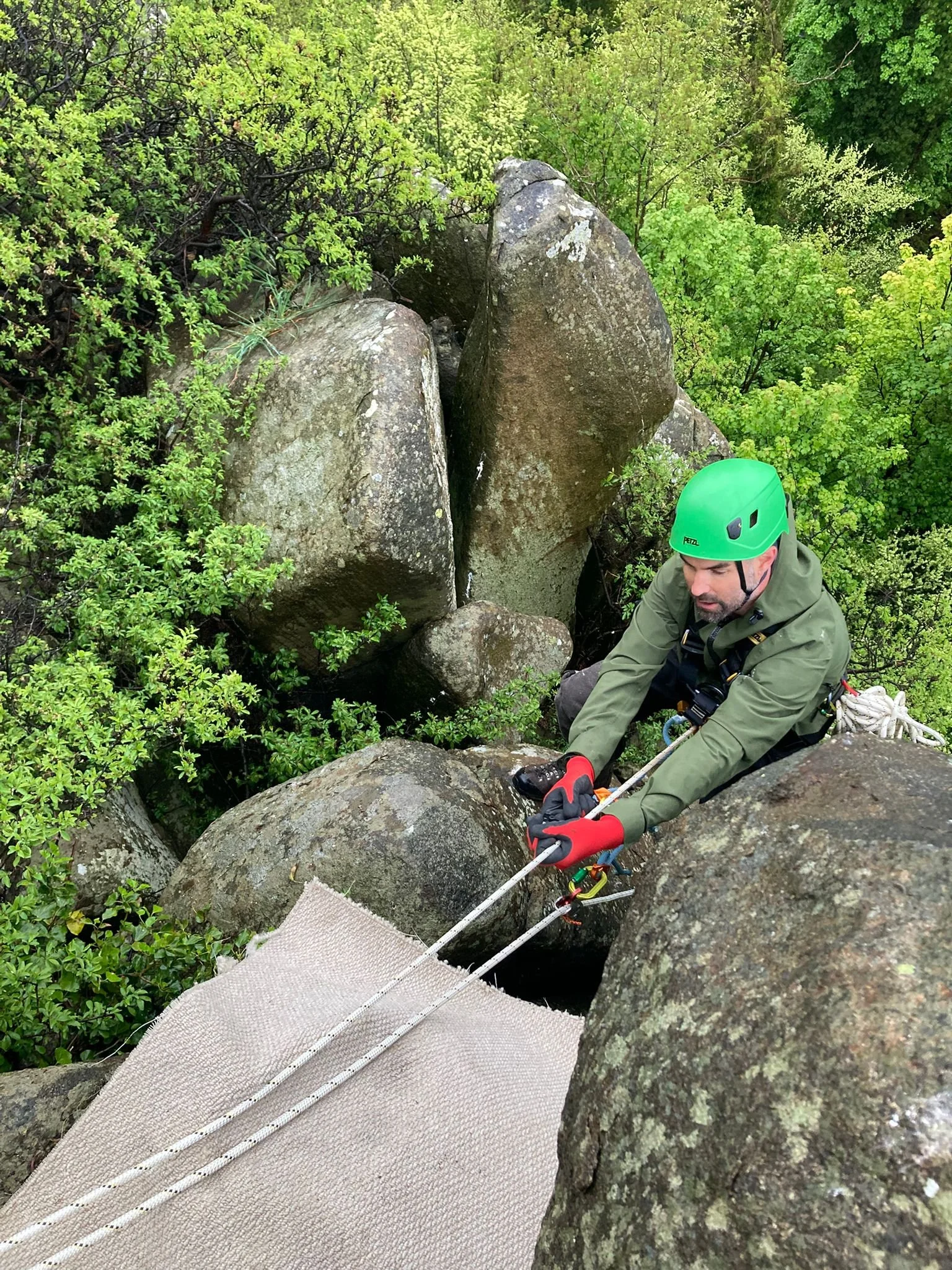 Rope access technician on ropes on cliff edge.