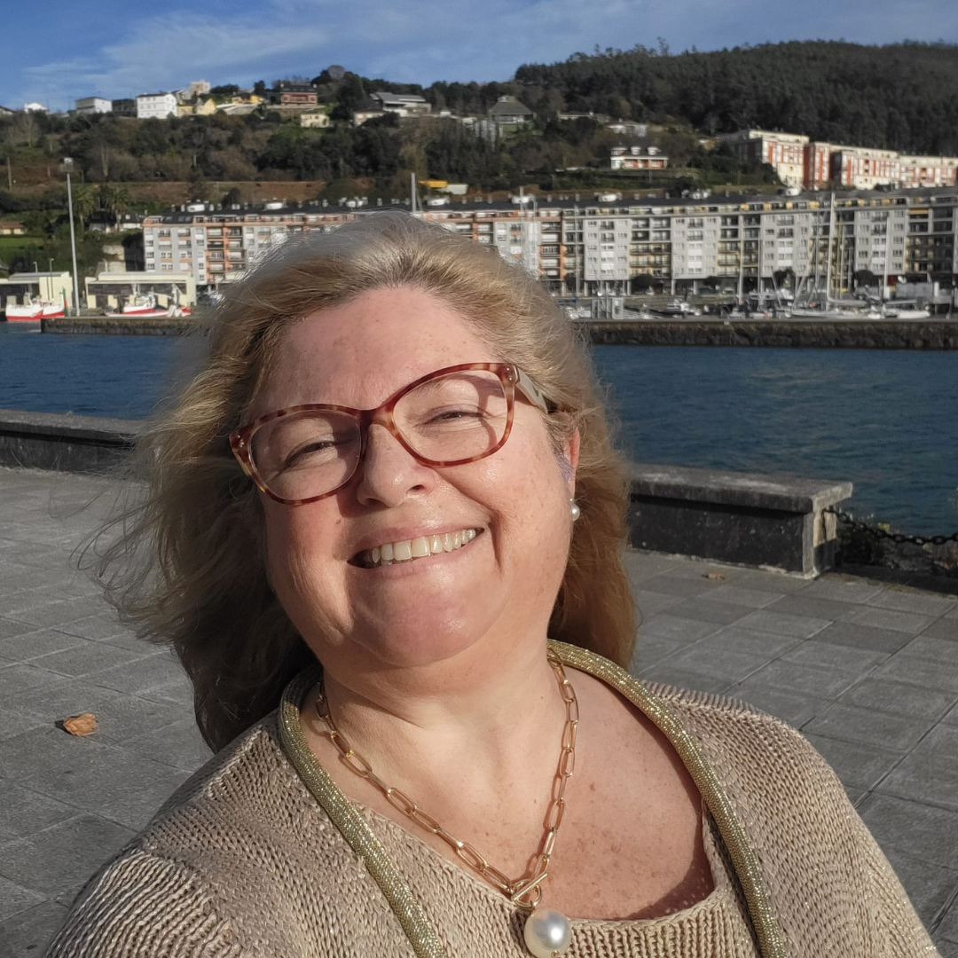 Verónica Moreno de Castro caminando sonriendo un día soleado  por el paseo marítimo de Viveiro - Lugo - España. Al fondo se ve la ría.