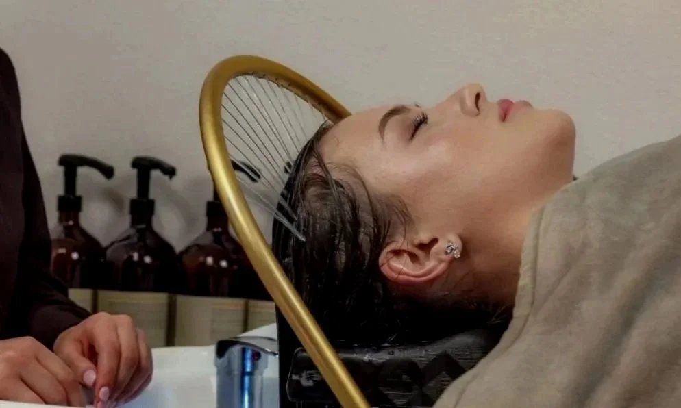 Une femme reçoit un traitement capillaire ou un shampooing dans un salon de coiffure.