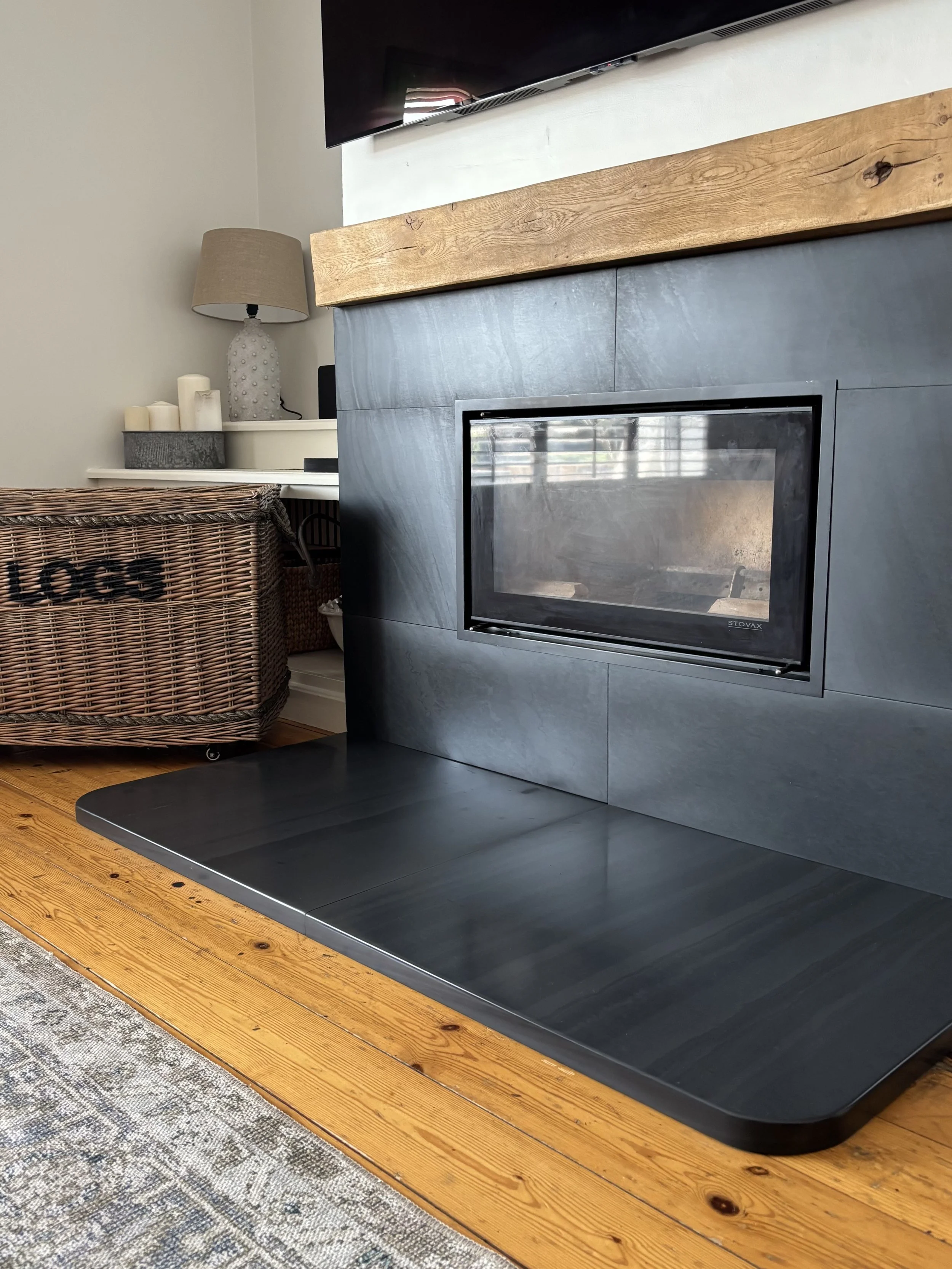 Polished Welsh slate hearth and matching surround for wall mounted wood burning stove.