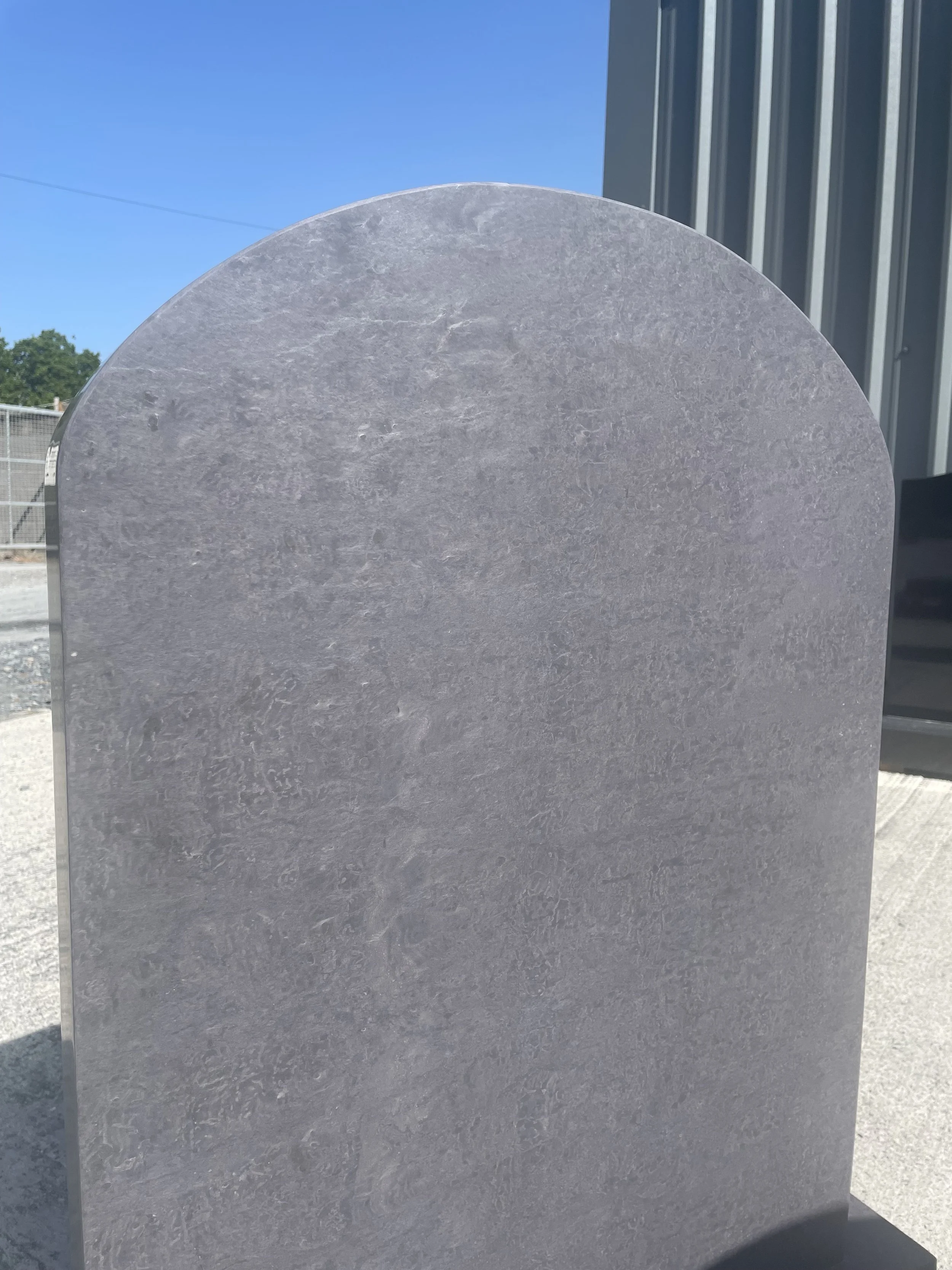 Close up of a curved top Valentia slate memorial, polished to a smooth finish.