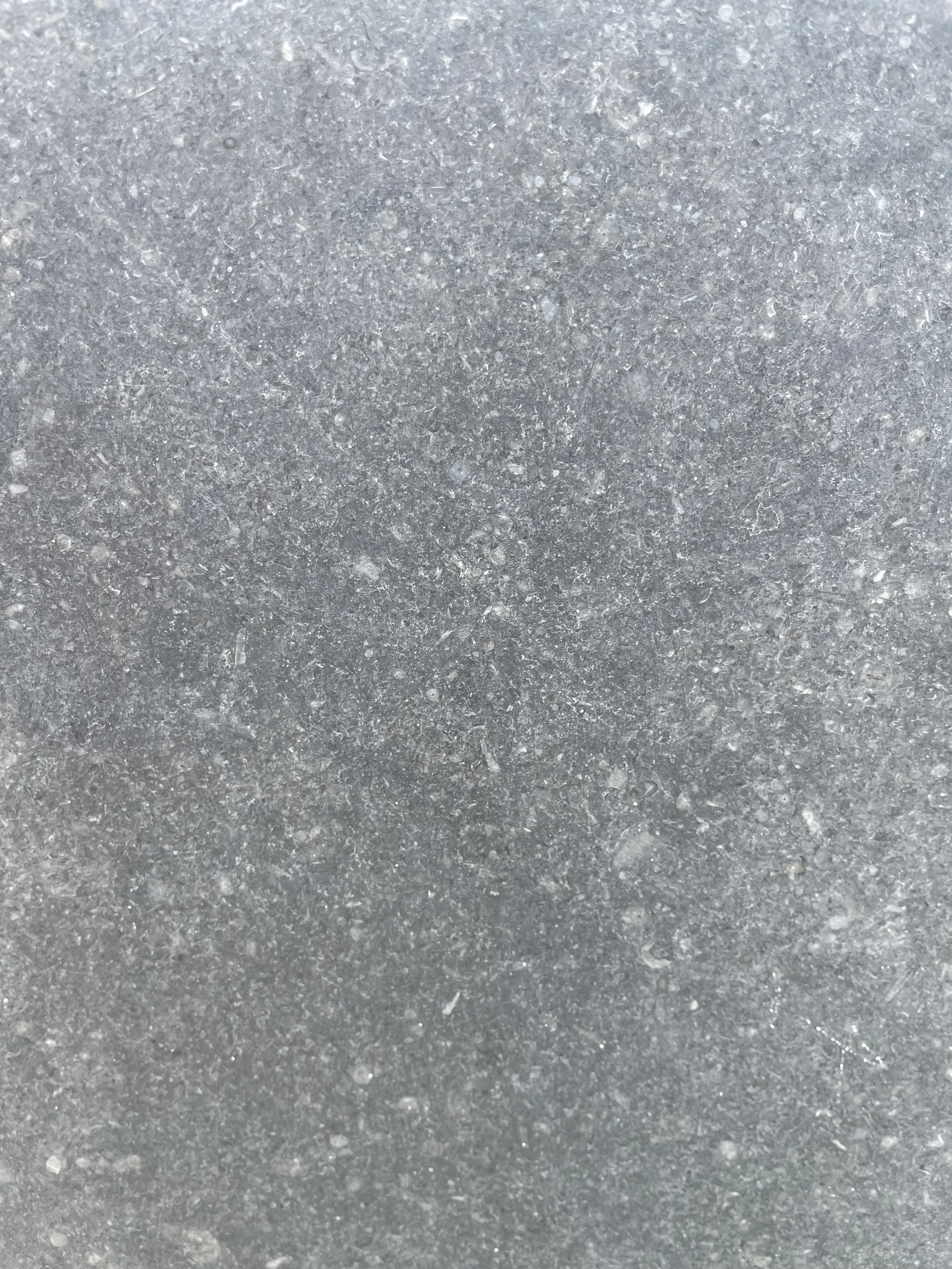 Close up of polished Kilkenny Limestone, a dark blue grey natural stone with subtle fossil markings, smooth surface and distinctive speckled texture.