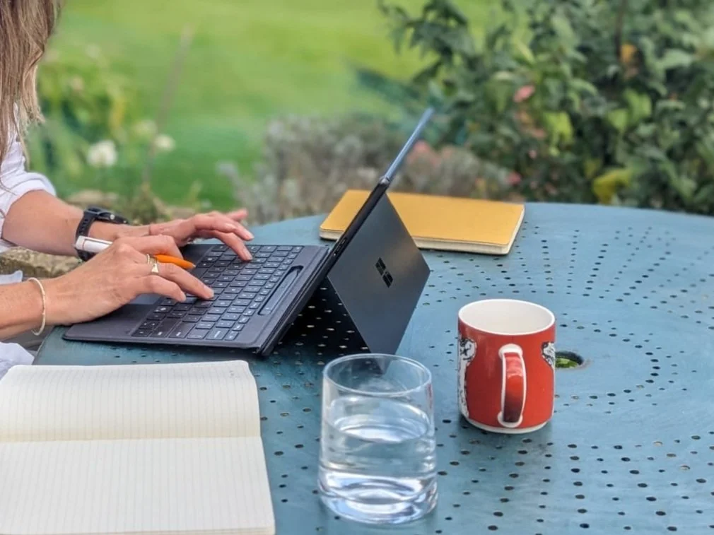 Hands working on a laptop outside