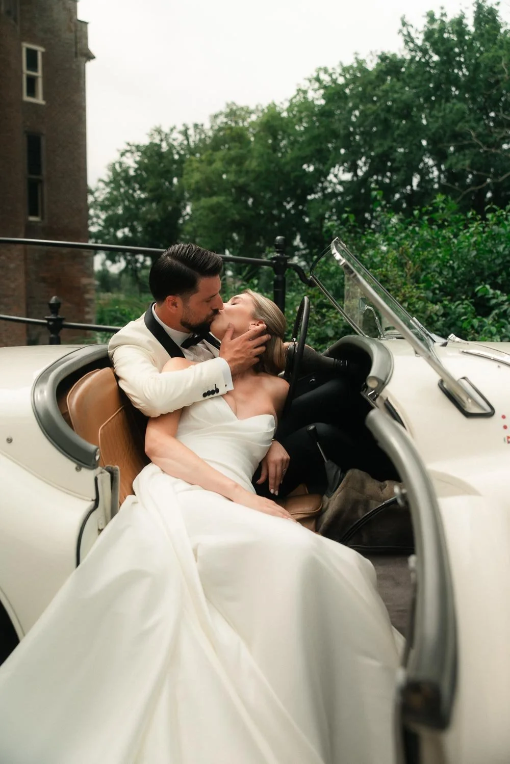 Bruid en bruidegom samen in de Jaguar tijdens de trouwdag