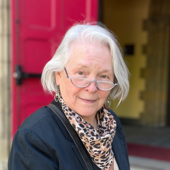 Ornate stained glass window with geometric designs, floral patterns, and a mix of pink, blue, and orange accents.