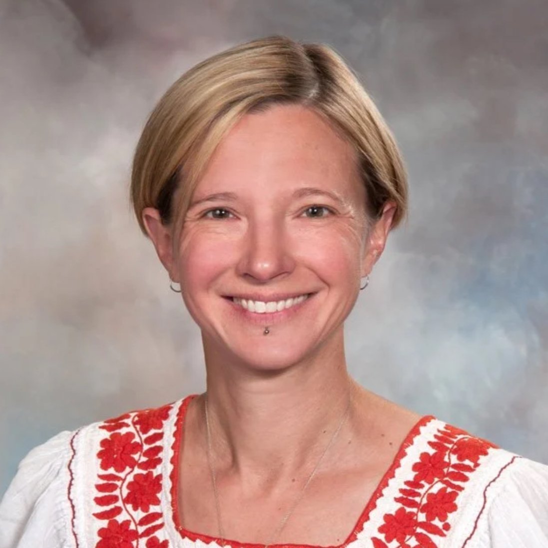 Colorful stained glass window featuring ornate floral patterns with purple, blue, and orange accents.
