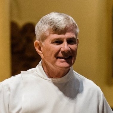 Ornate stained glass window with floral patterns, purple, blue, and amber accents.