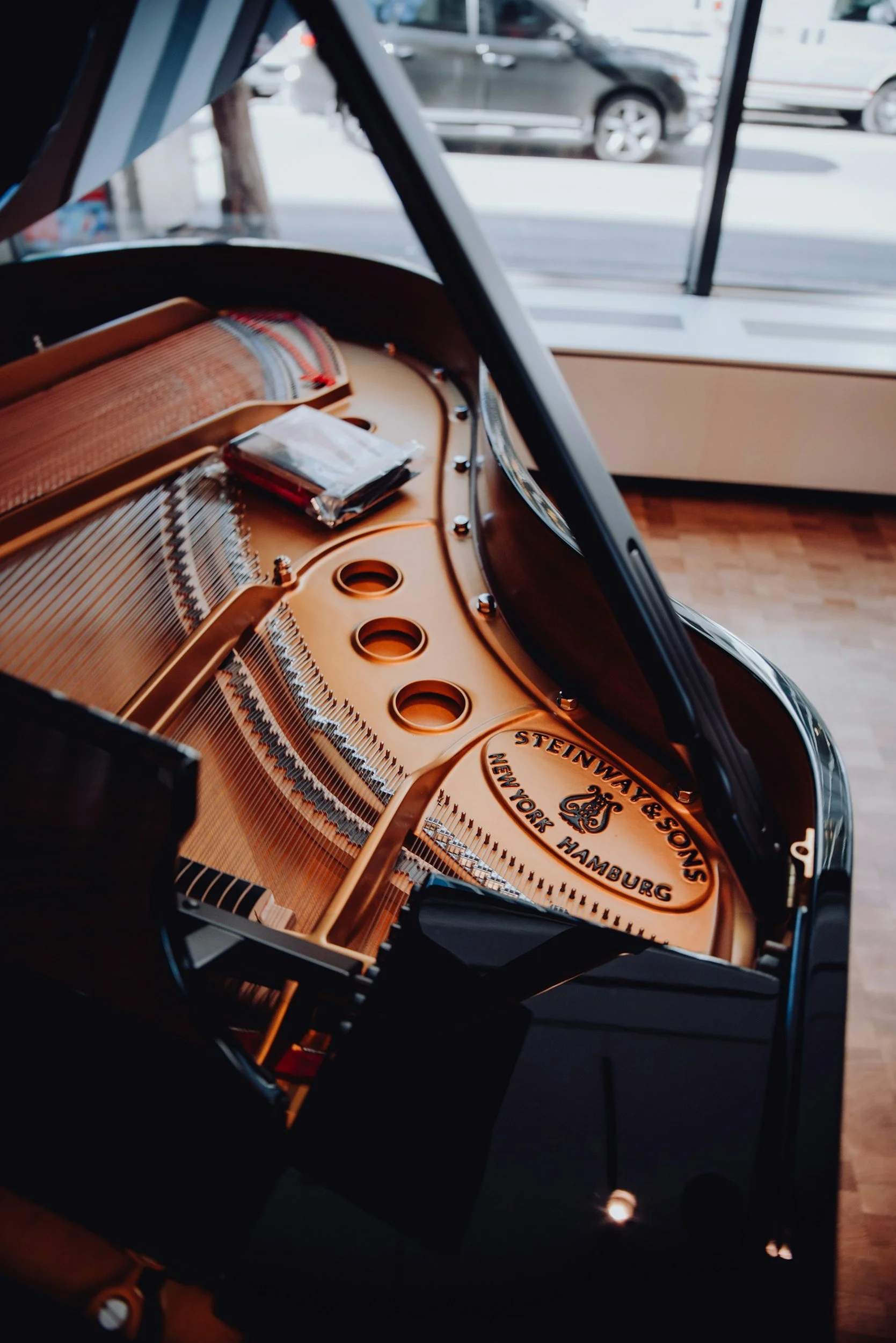 Close-up of a grand piano inside a store, with the inside strings and a sticker showing the brand 'Steinway & Sons, New York, Hamburg'.