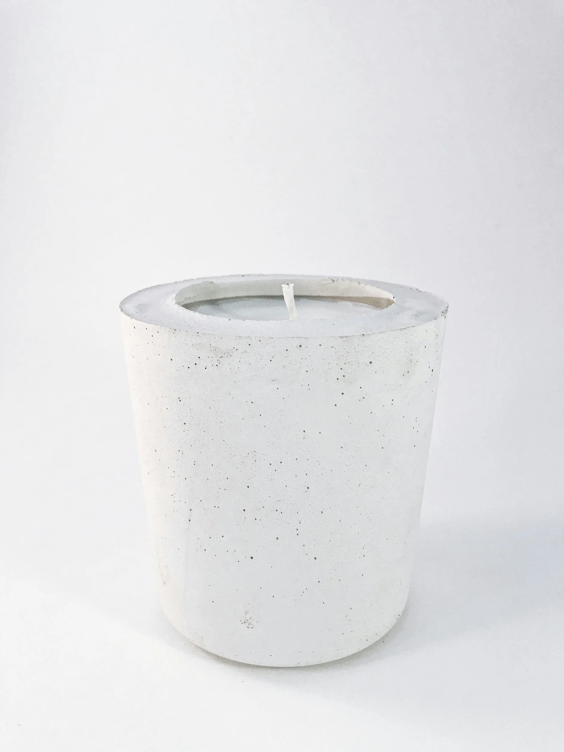White ceramic candle holder with a tea light candle inside against a plain white background.