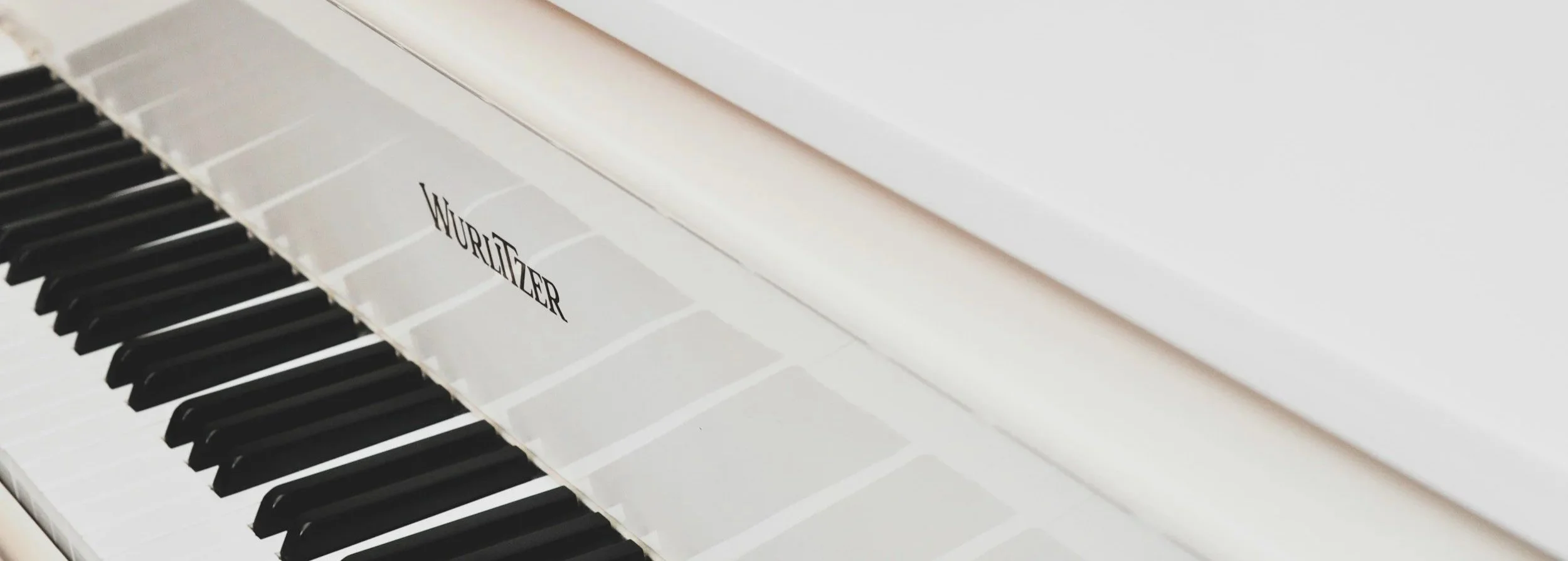 Close-up of a white Wurlitzer piano keyboard with black and white keys.