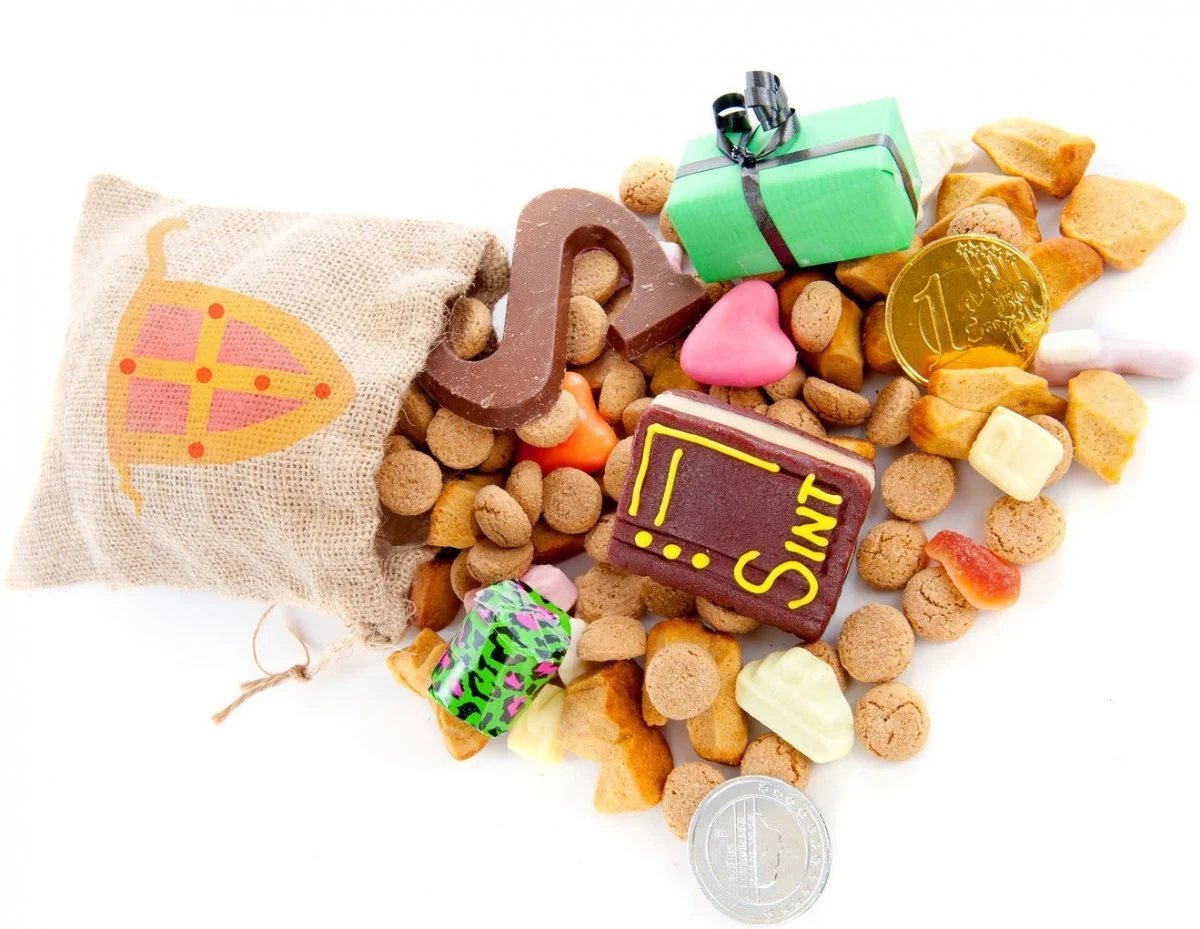 Een open zakje met een print van een sinaasappel en verschillende snoepjes en een munt