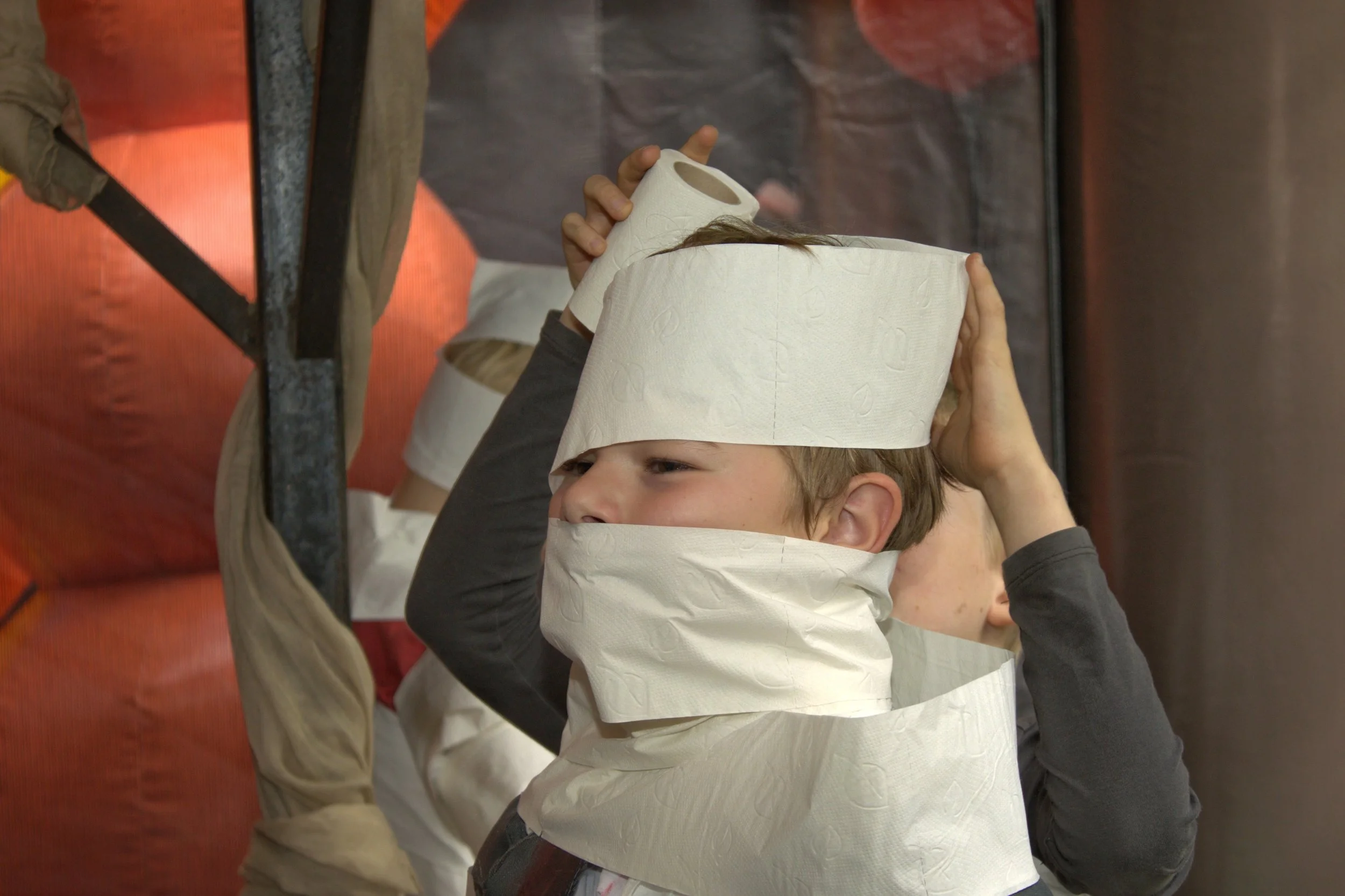 Een kind met een hoed en een halsdoek gemaakt van wit toiletpapier.