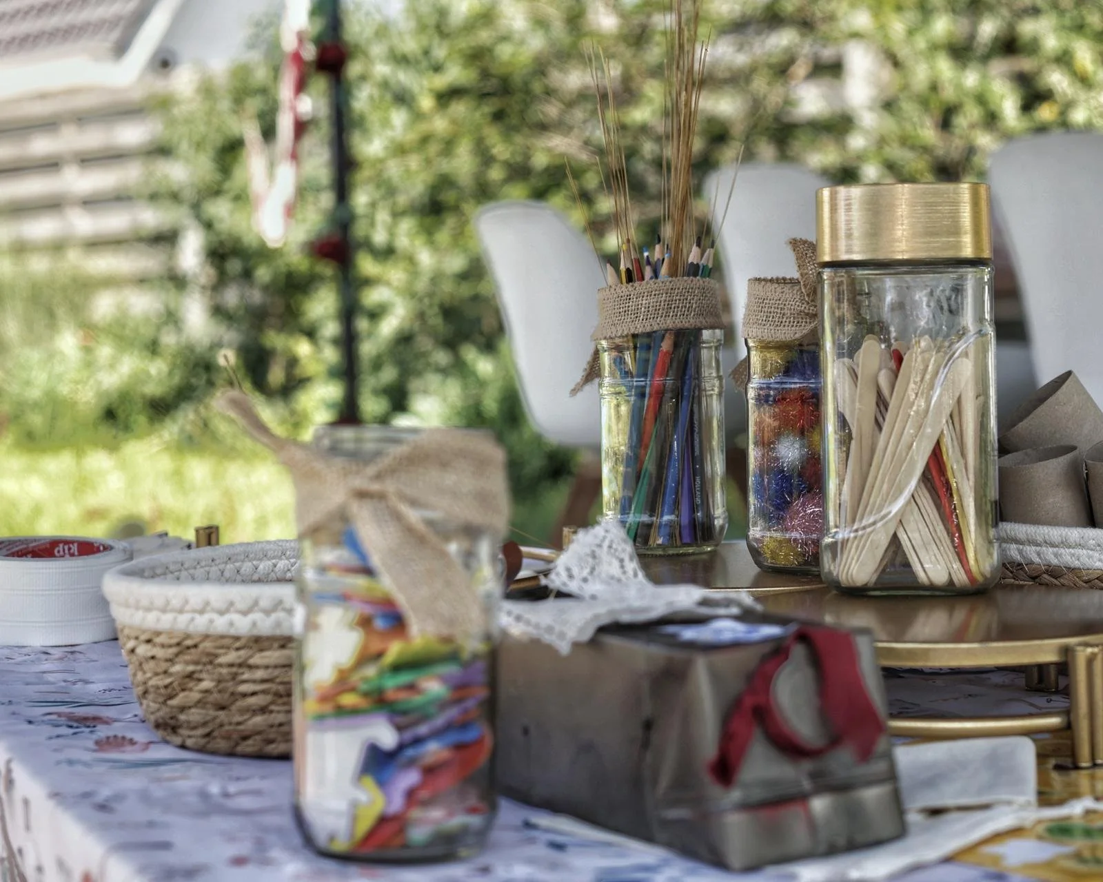 Decoratieve glazen potten gevuld met kleurrijke kerstversieringen en snoepstokjes op een tafel buiten.