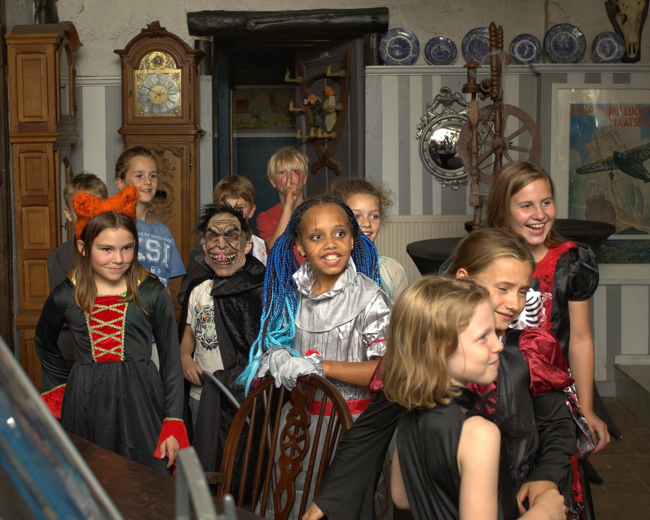 Kinderen in diverse kostuums, waaronder een heks, een vos en een clown, die waarschijnlijk op een feestje of verkleedpartij zijn.