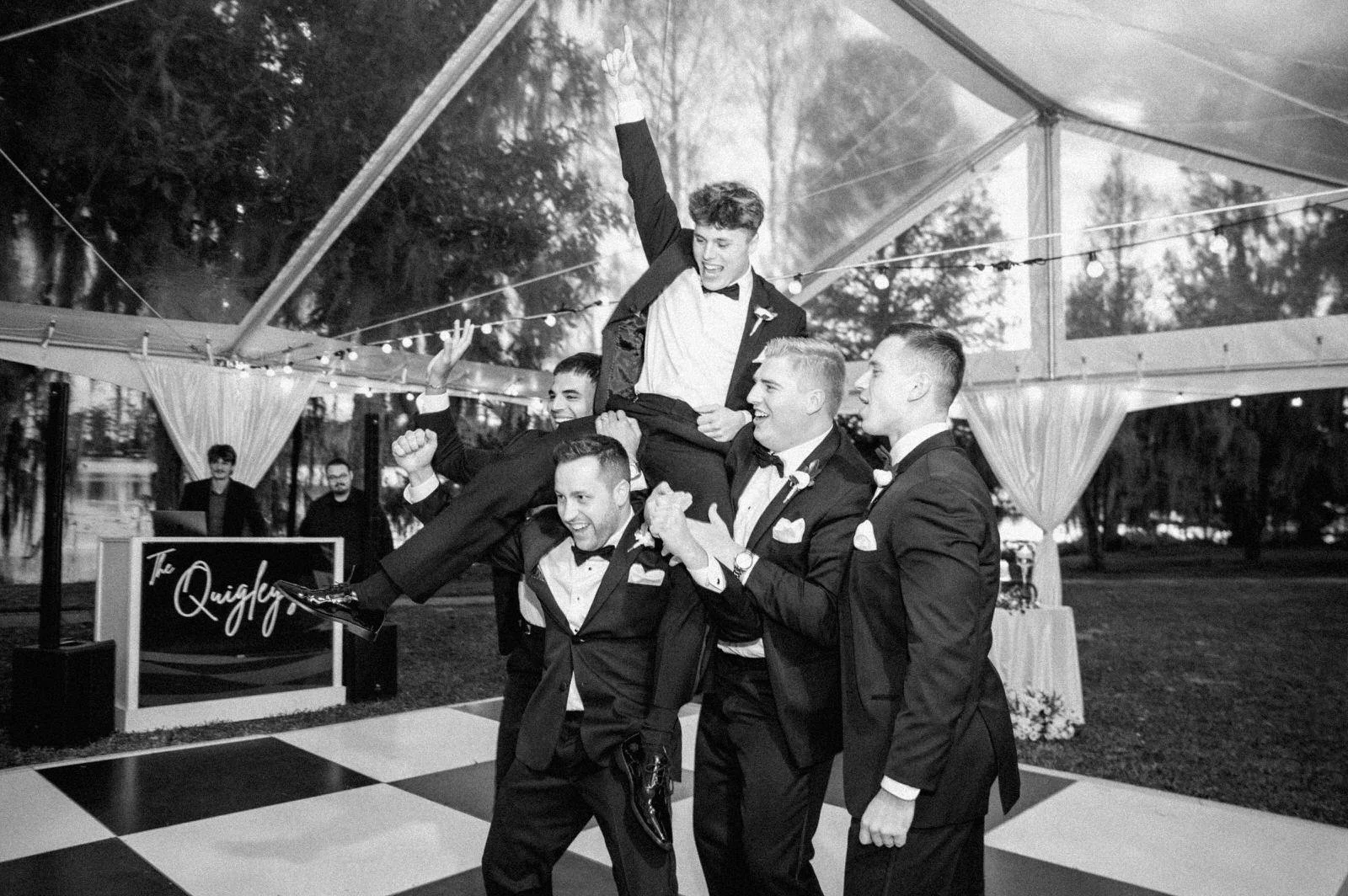 Groom enjoying the tented reception at Cypress Grove Estate, Orlando, candid moment during a rainy Central Florida wedding (Joanna Moore Photography).	