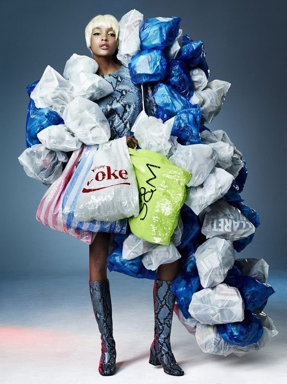 Fashion model carrying multiple plastic shopping bags to highlight the environmental impact of fast fashion and overconsumption. Editorial photo promoting sustainable style and conscious consumerism