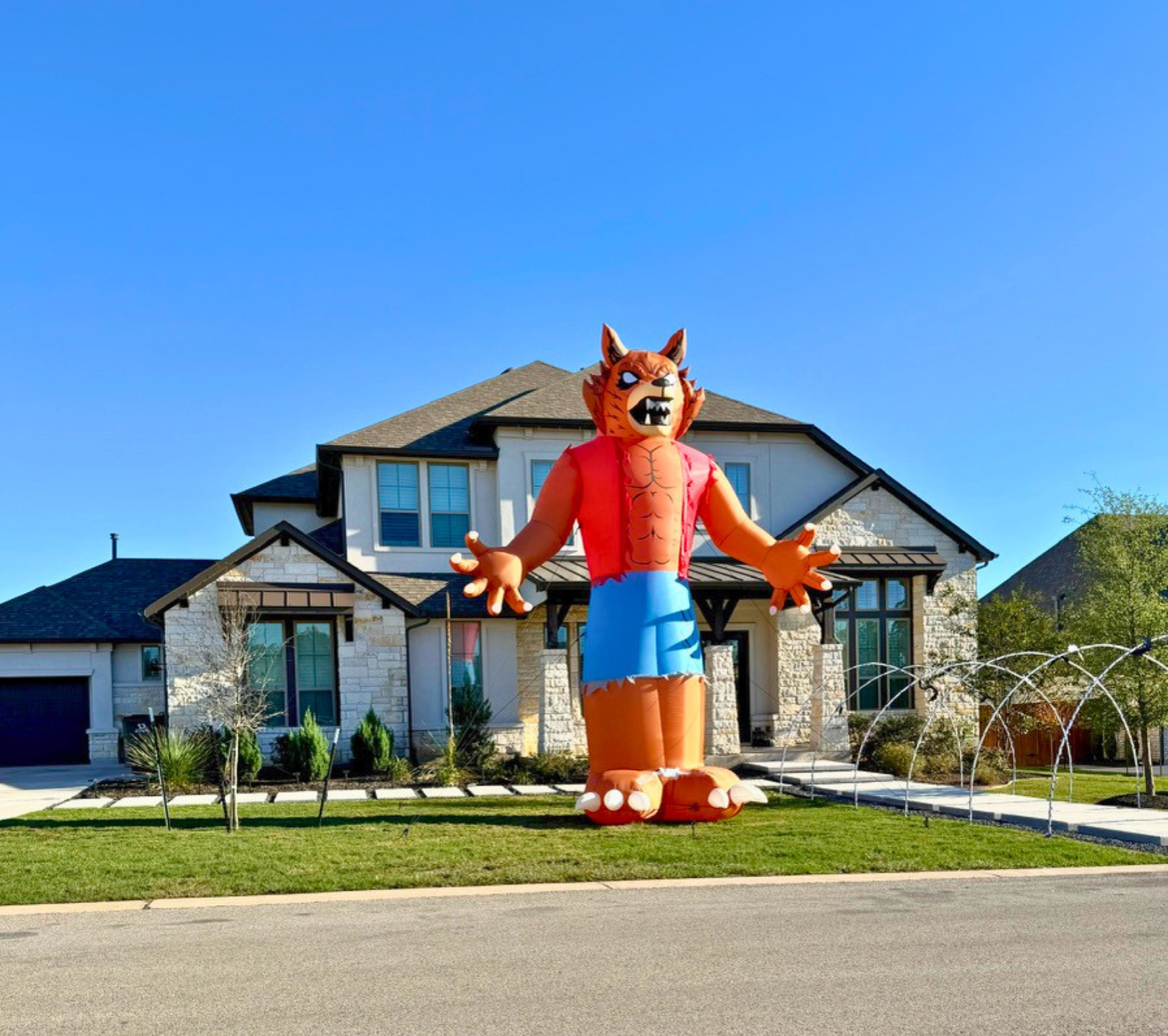 Large inflatable dragon figure in front of a modern house with front yard and water fountains